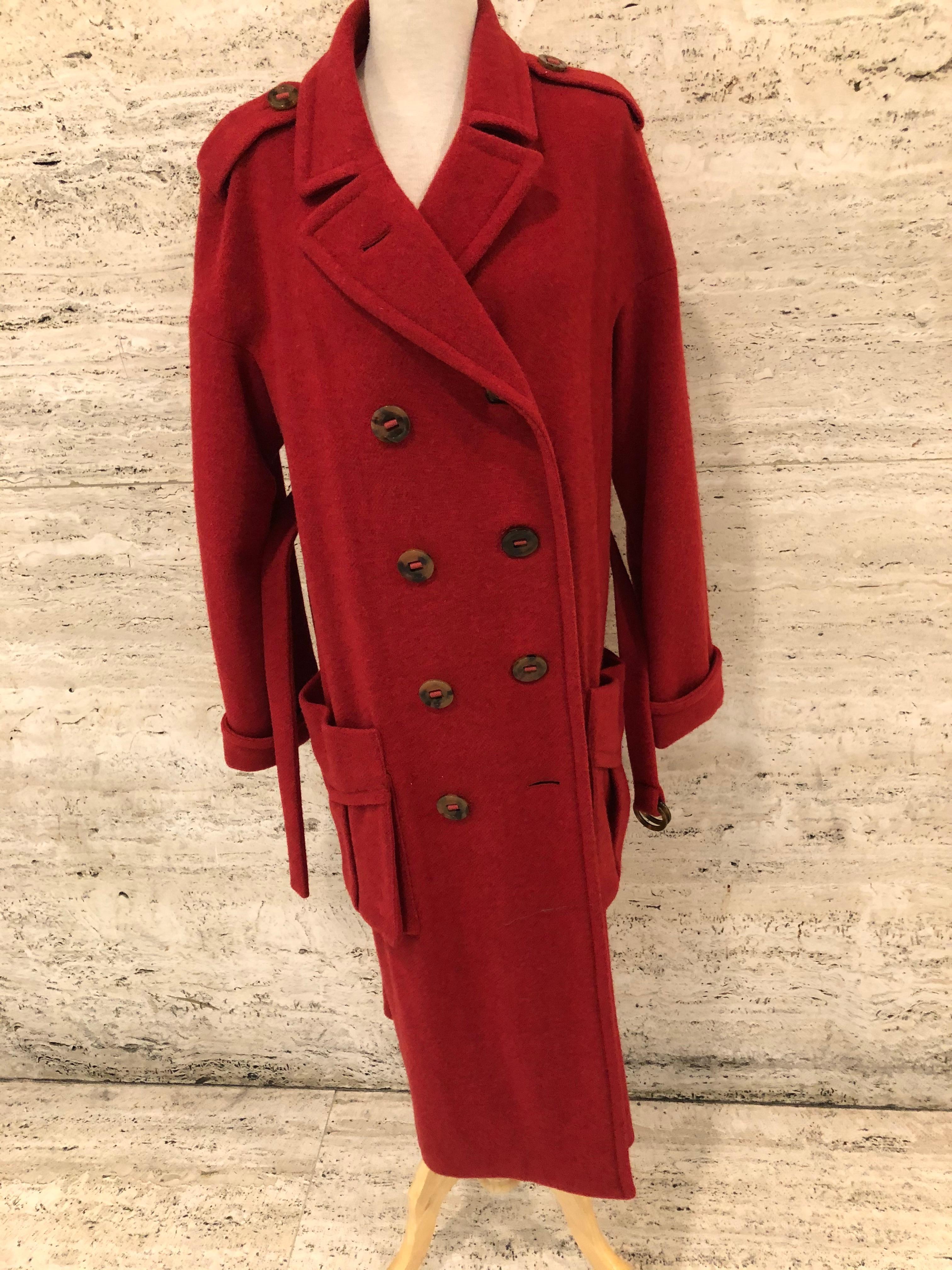 Elegant wool coat by Sonia Rykiel in a vibrant red colour. vintage.
Trench style, dubbel breasted with flap pockets and dropped shoulders.
Cuffed sleeves, brass buttons with 2 loops for the 2 belts.
Only top of coat and sleeves are lined, lining is