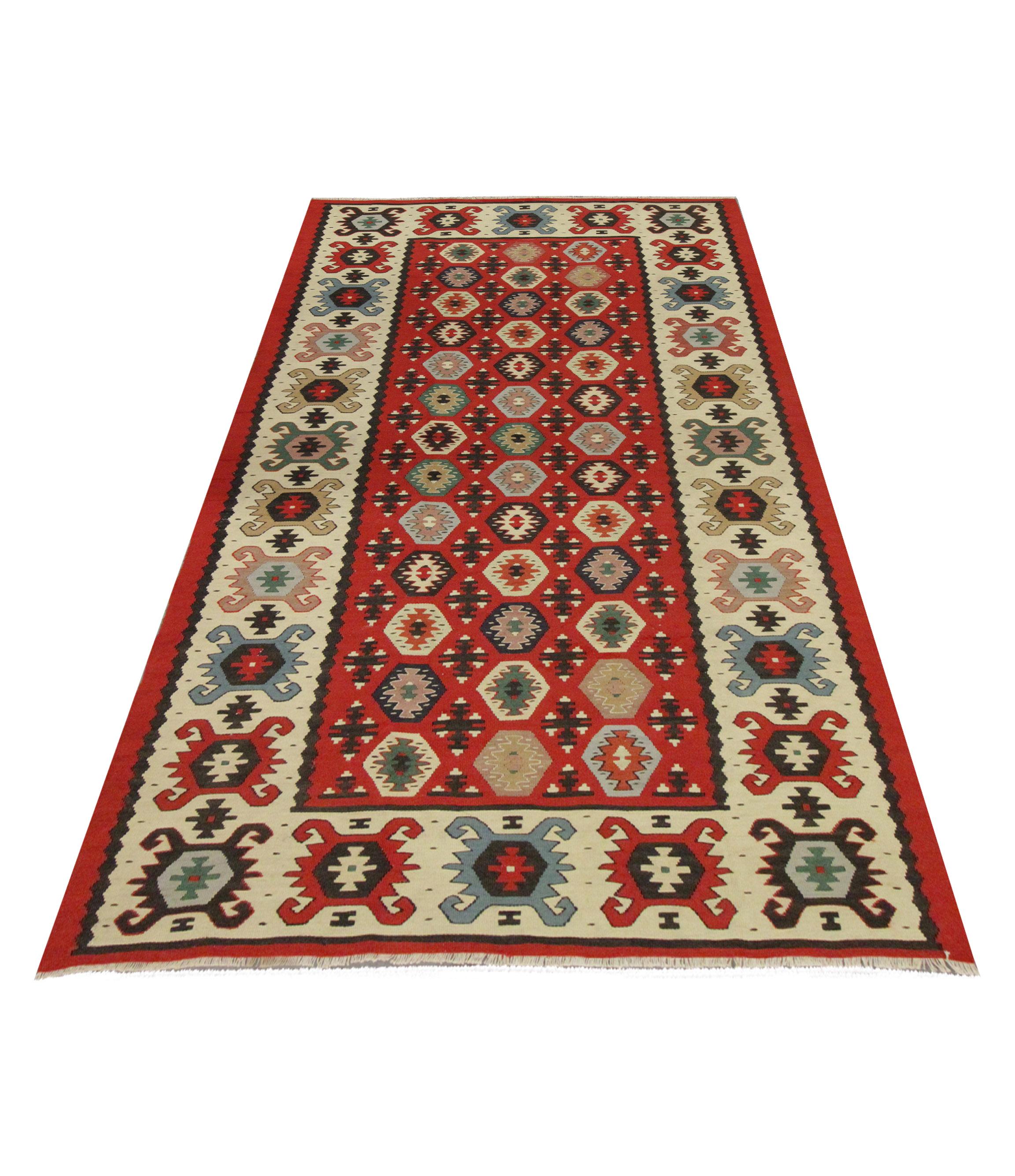 This area rug is a handwoven kilim from Sarkoy, Turkey woven by hand in the 1960s. The design has been woven on a rich red background with beige, blue pink and brown accents that make up the eye-catching geometric design. The rich colour palette and