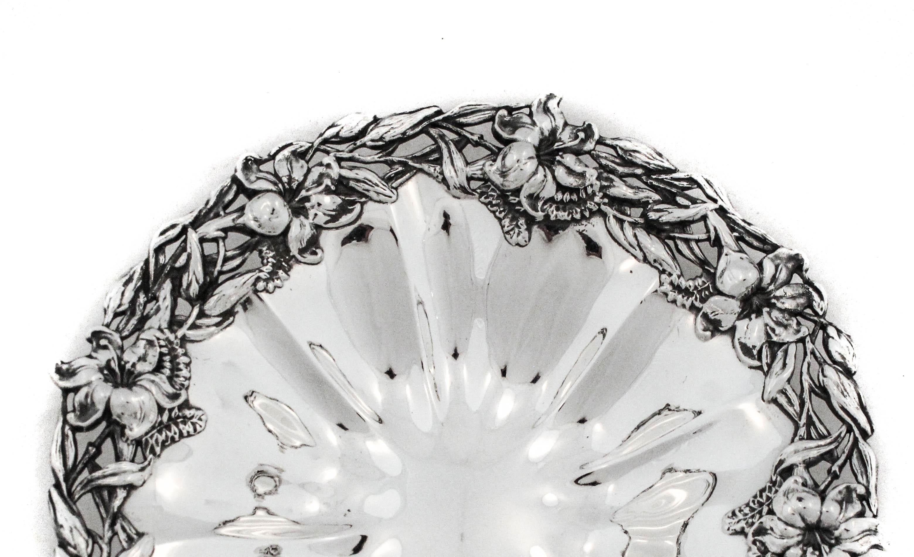 This sterling silver bowl by Redlich & Company exemplifies the Art Nouveau style, popular in the late nineteenth century. The wide border is cast and chased in high relief with a luxuriant arrangement of blossoms, buds, and leaves, rendered with the