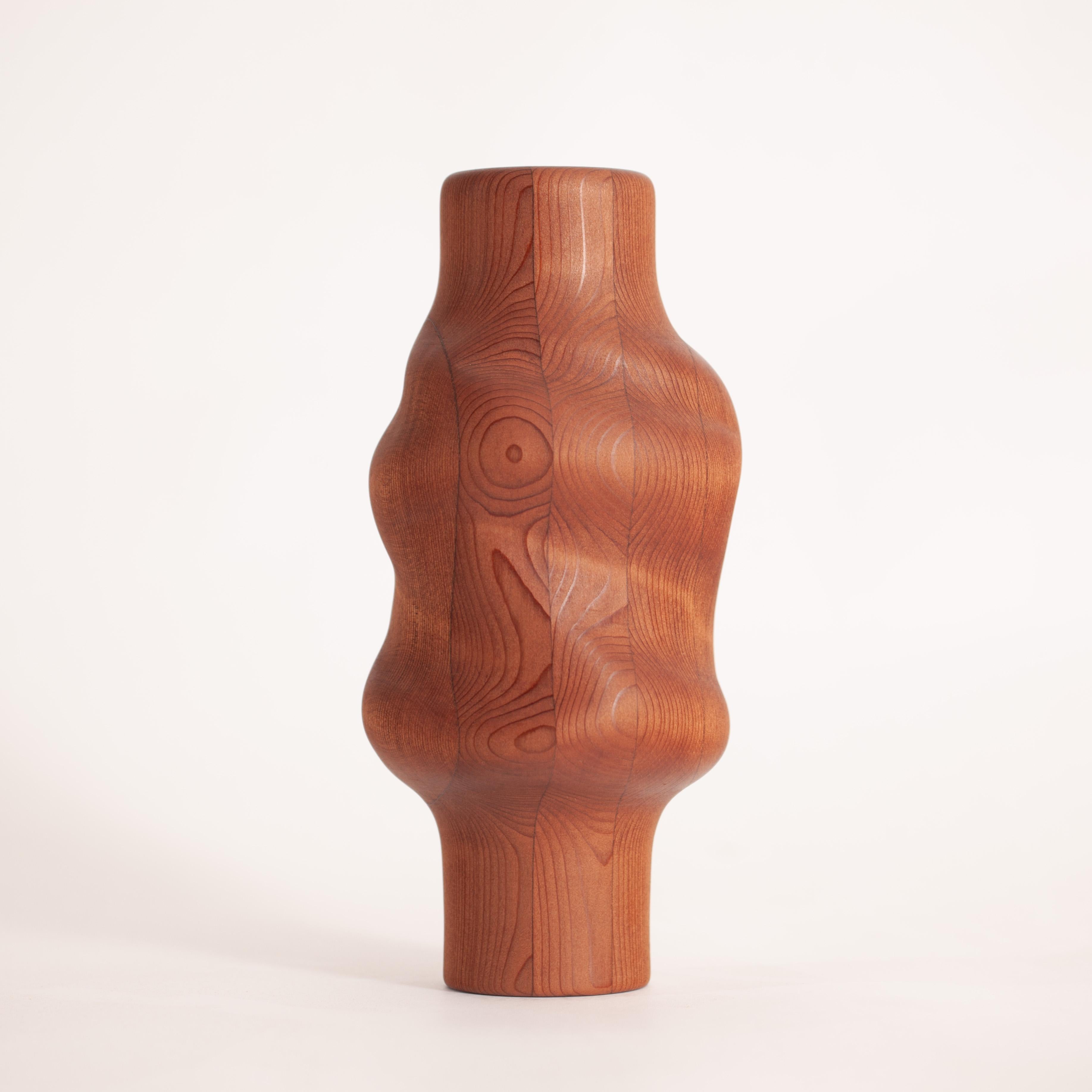 Svitok-Vase aus aufgearbeitetem Rotholz. Inspiriert von den Ästen und Windungen der Bäume, die an einen Stoffknoten erinnern. Die unregelmäßigen Formen und Falten im Holz regen die Neugierde an, genau wie ein Spaziergang im Freien und das Staunen