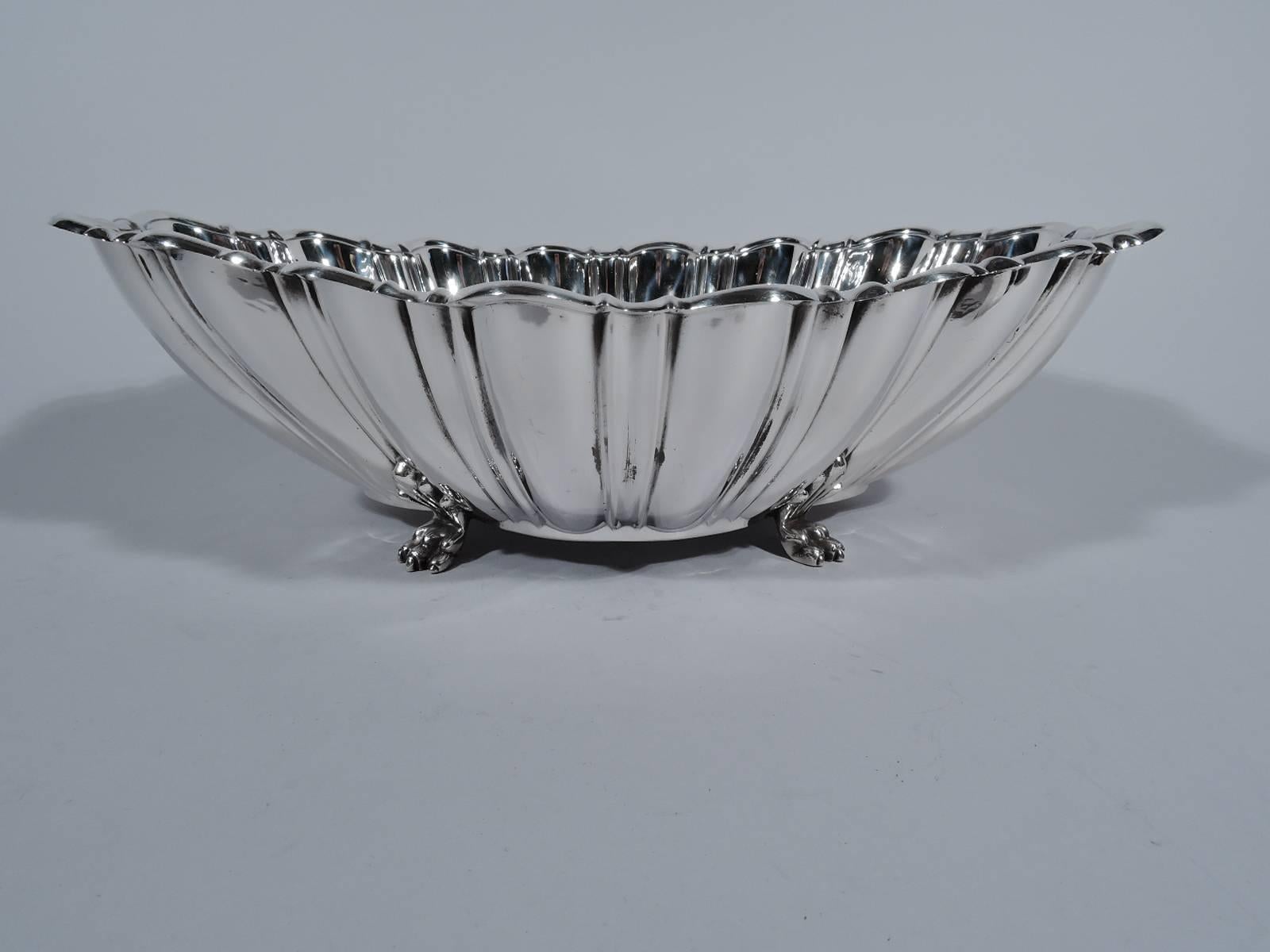 Modern Classical sterling silver centrepiece bowl. Made by Reed & Barton in Taunton, Mass. Quatrefoil well. Curved sides with alternating flutes and lobes. Scrolled rim. Rests on four paw supports with palmette mounts. A great revving up of
