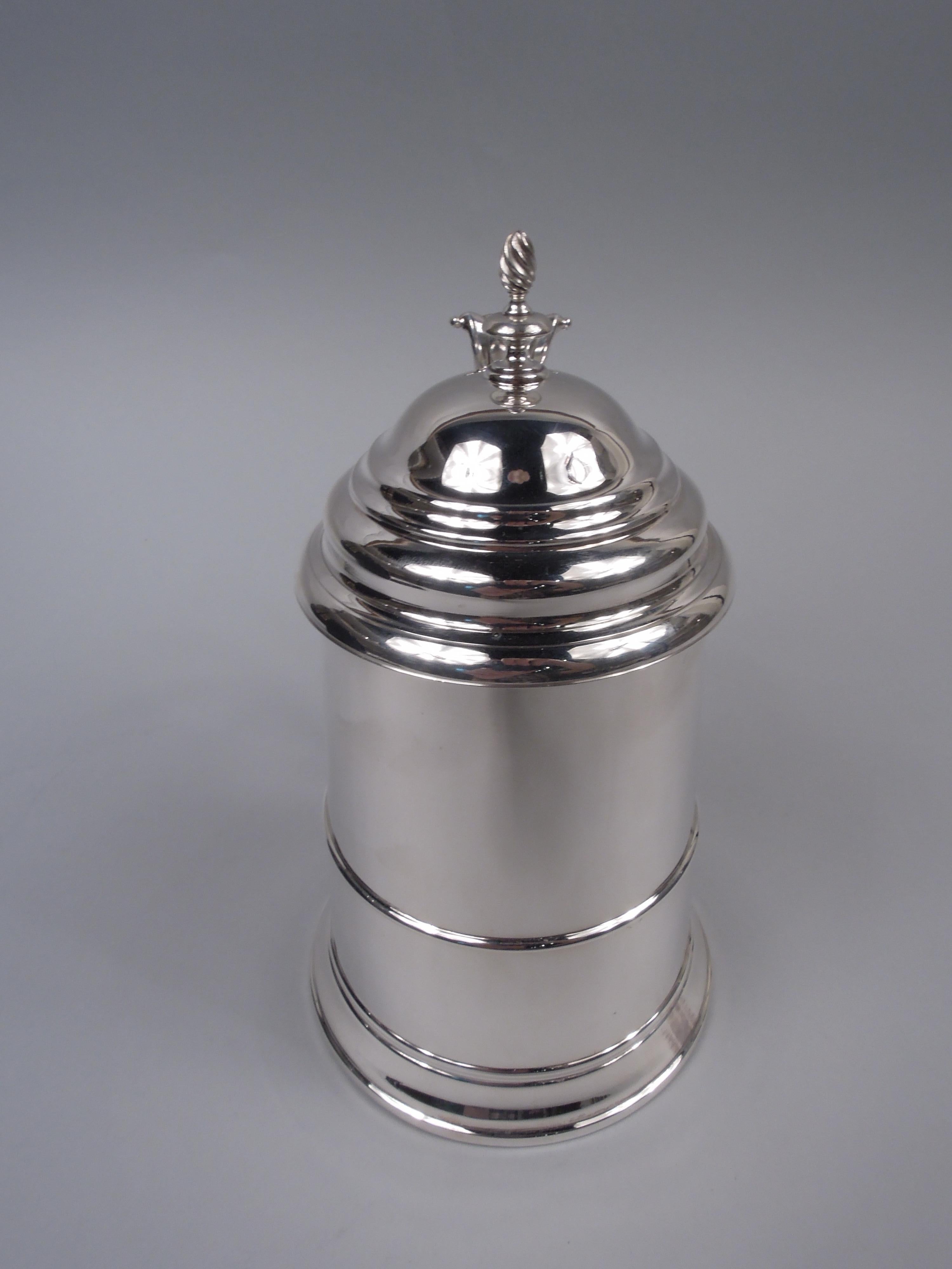 Tasse en argent sterling de l'époque coloniale américaine. Fabriqué par Reed & Barton à Taunton, Mass. Cuvette en forme d'ogive, effilée vers le haut, avec un pied étalé. Couvercle à charnière et à gradins avec fleuron torsadé. Poignée à volute en S