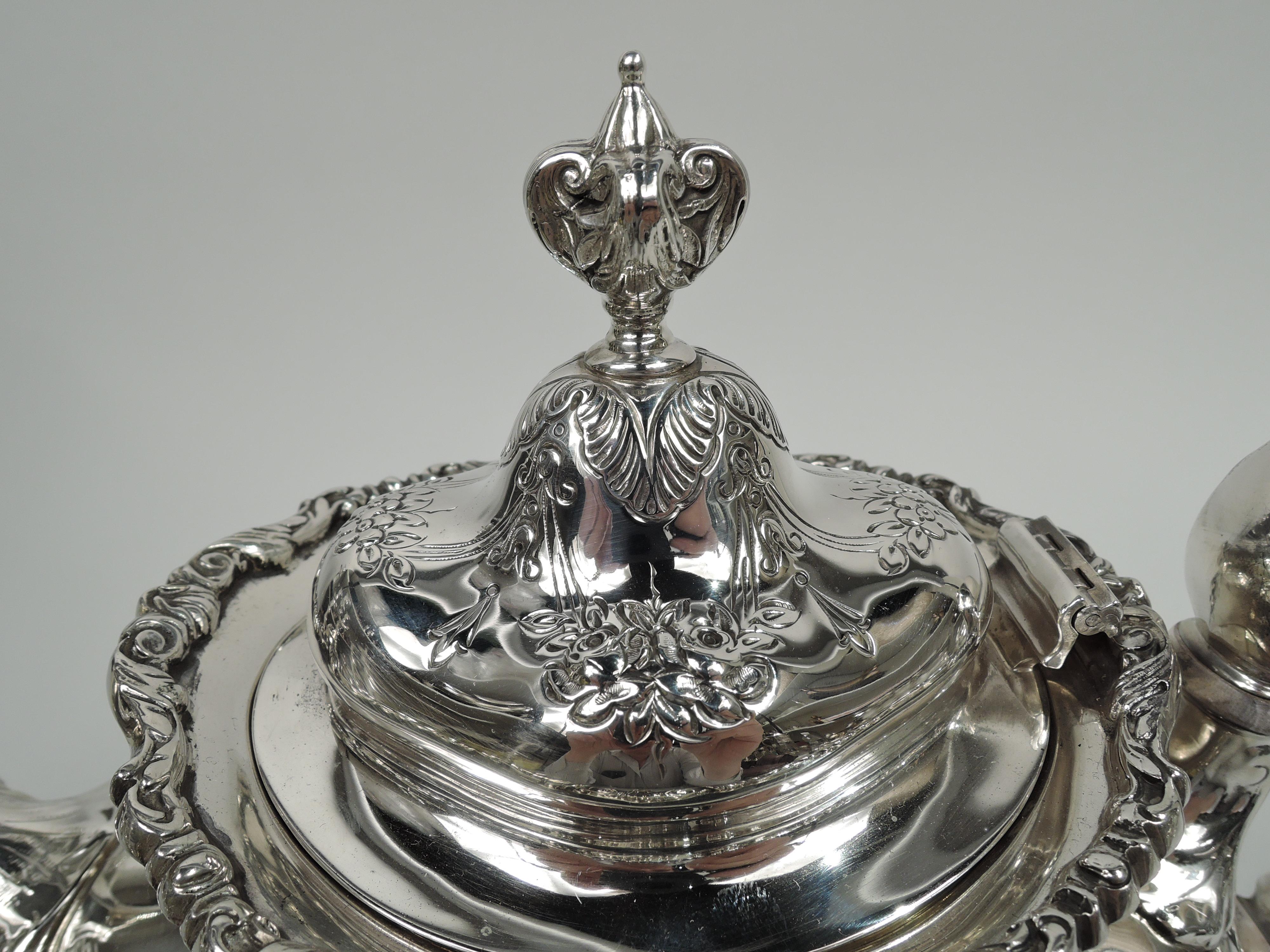 Francis I sterling silver teapot. Made by Reed & Barton in Taunton, Mass. Bellied ovoid body on domed foot, high-looping leaf-capped scroll handle, and leaf-capped s-scroll handle; cover hinged and domed with leafing-scroll quatrefoil finial.