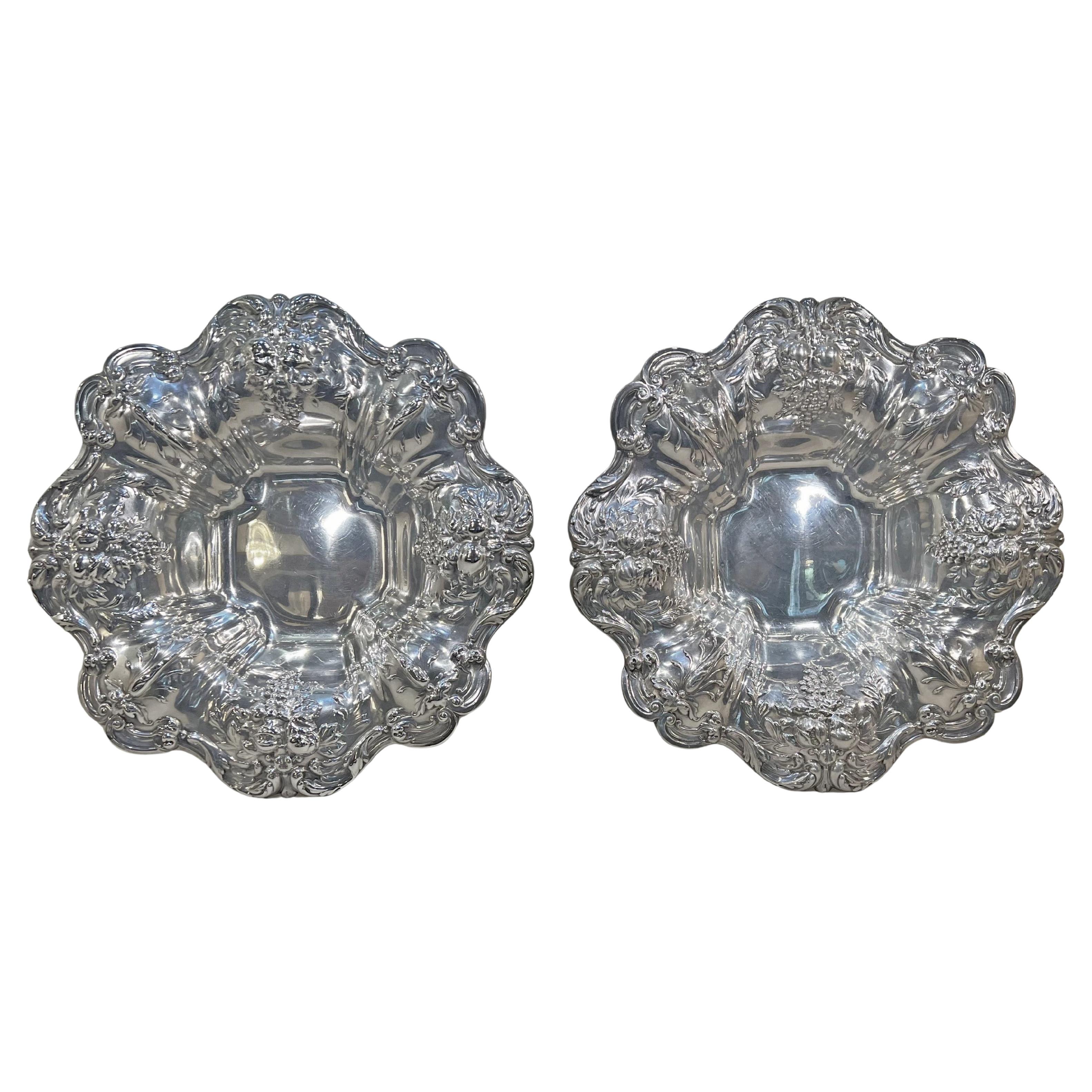 Pair of footed Reed & Barton Francis I fruit bowls in sterling silver, each featuring a border decorated with scrollwork, leaves, blossoms, and fruit, as well as curled tip feet decorated with acanthus leaf design.  Square form center measures