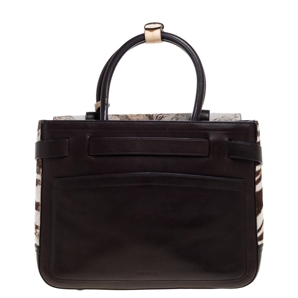 This Boxer tote bag from Reed Krakoff is crafted from zebra-printed calfhair and leather in lovely dark brown & beige hues. It features buckled belt straps on the exterior. The open-top leads to an interior that has a fabric lining and features zip