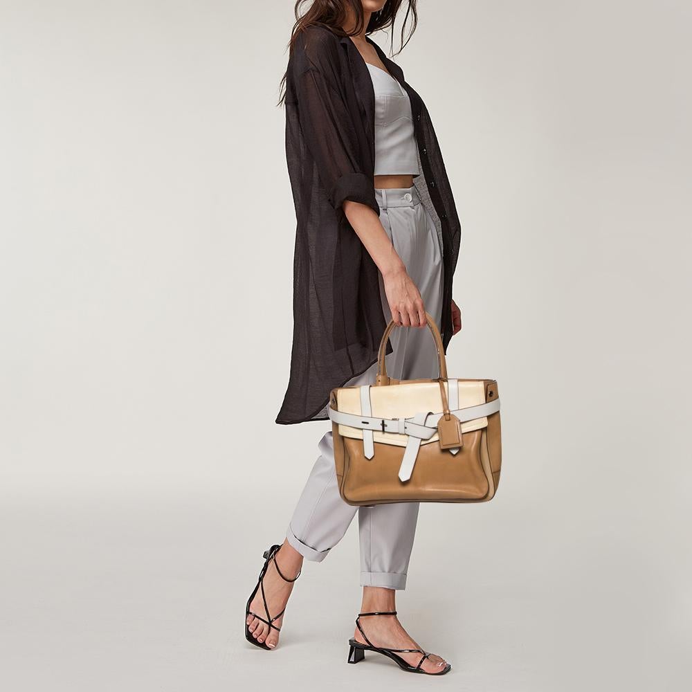 This Reed Krakoff Boxer tote features belt detailing at the front and is crafted from tan/cream leather. It is equipped with dual handles, straps in white, and a fabric-lined interior that has enough space to hold all your daily essentials.


