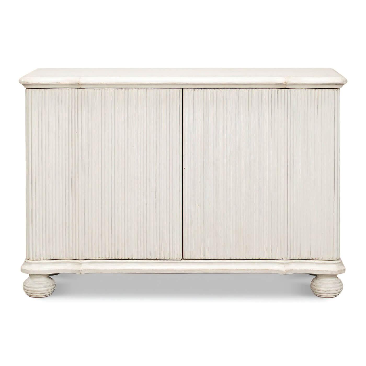 A reeded antique white cabinet crafted from reclaimed pine. It features a decorative ribbing running top to bottom on the front and sides and molded edging along the top. 

Dimensions: 53