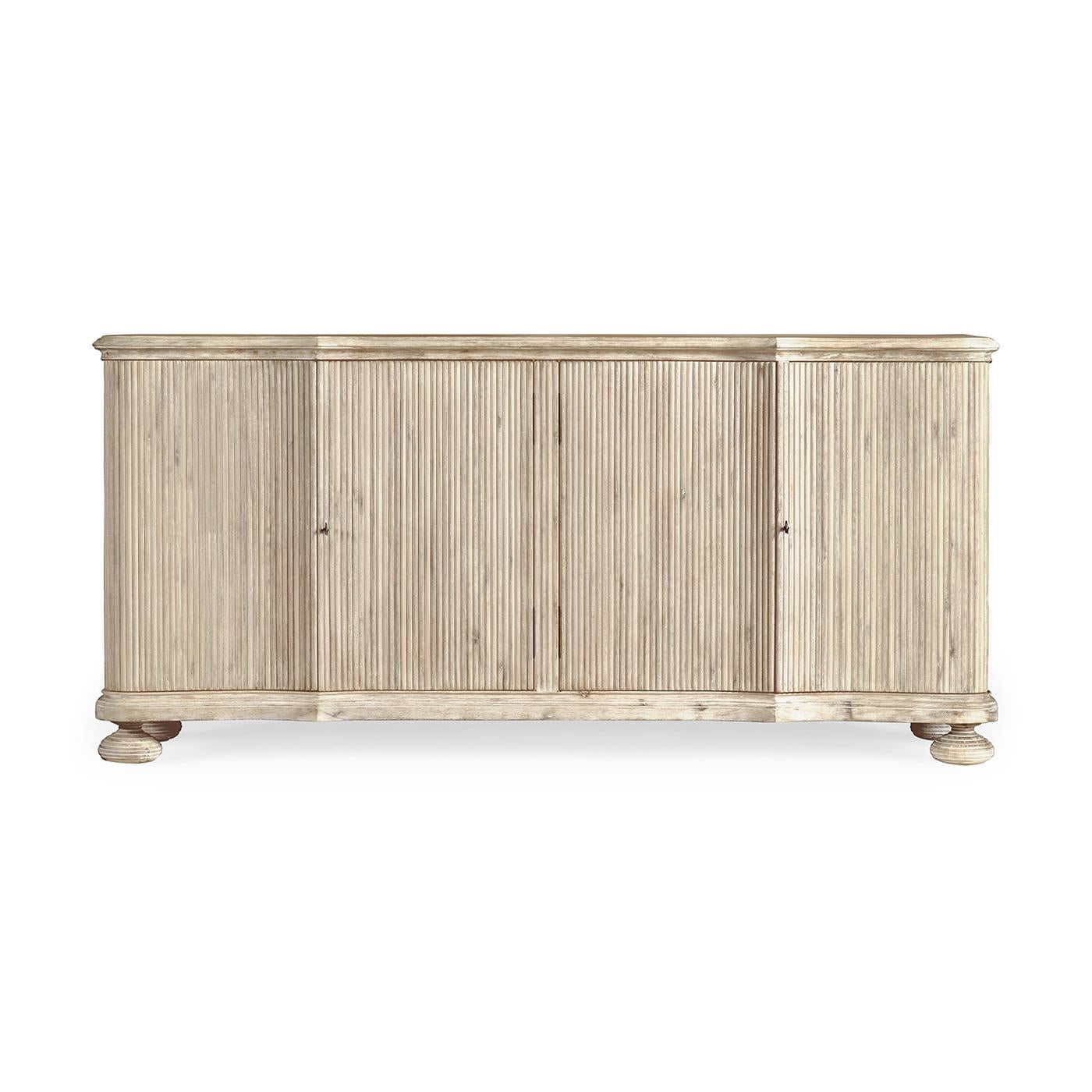 Un buffet moderne en acacia blanchi à la chaux, avec des côtés cannelés, un plateau à bord mouluré, un intérieur peint avec des étagères réglables, et reposant sur des pieds en forme de chignon.

Dimensions : 72.5
