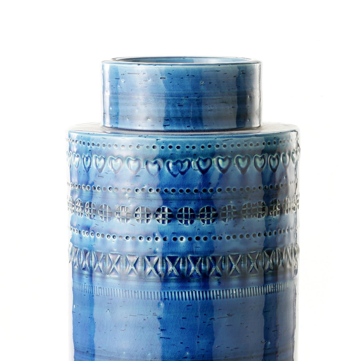 This exquisite small vase is in white clay with a striking turquoise finish. Its rectangular shape with a smaller base and top evokes the shape of a reel and features a series of parallel geometric carvings running all around its central body. This