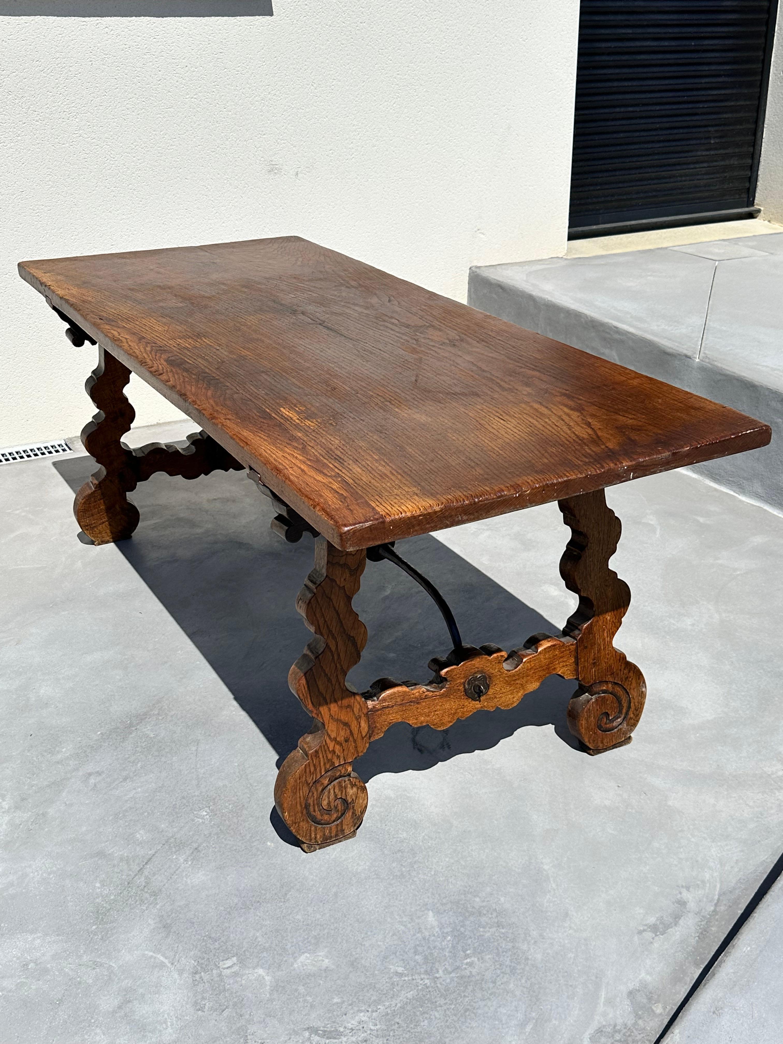 Spain regionalist, refectory table.

Solid walnut and wrought iron.
The top supported by sulpted uprights in the shape of a lyre joined by wrought iron rods: accidents, traces of worms (the table has been treated).

Nice patina.

19th century.