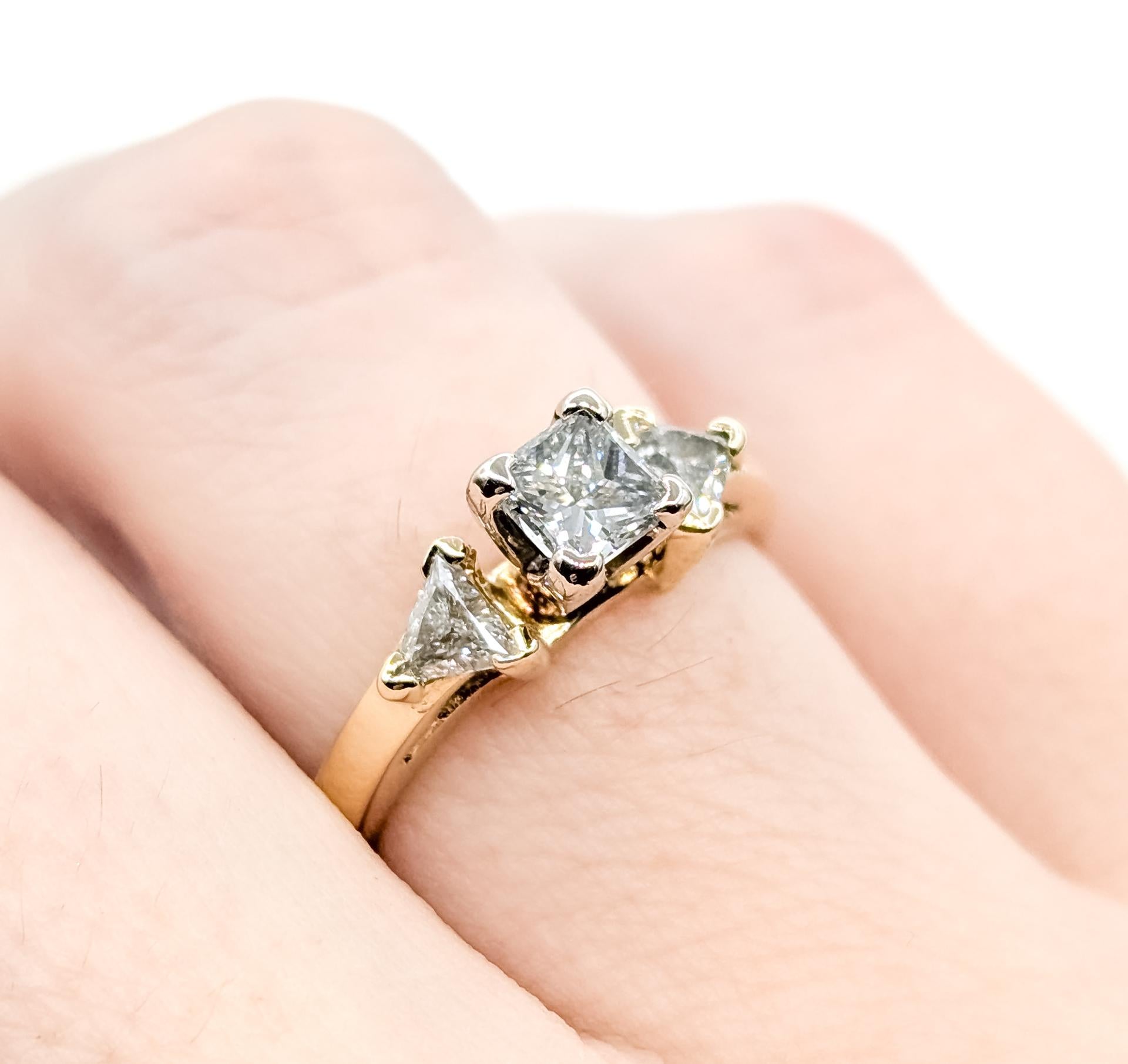 Questo anello è finemente realizzato in oro giallo 14k e mette in mostra tre diamanti incastonati in una disposizione a tre pietre senza tempo. Il diamante centrale con taglio princess è splendidamente affiancato da due diamanti laterali con taglio