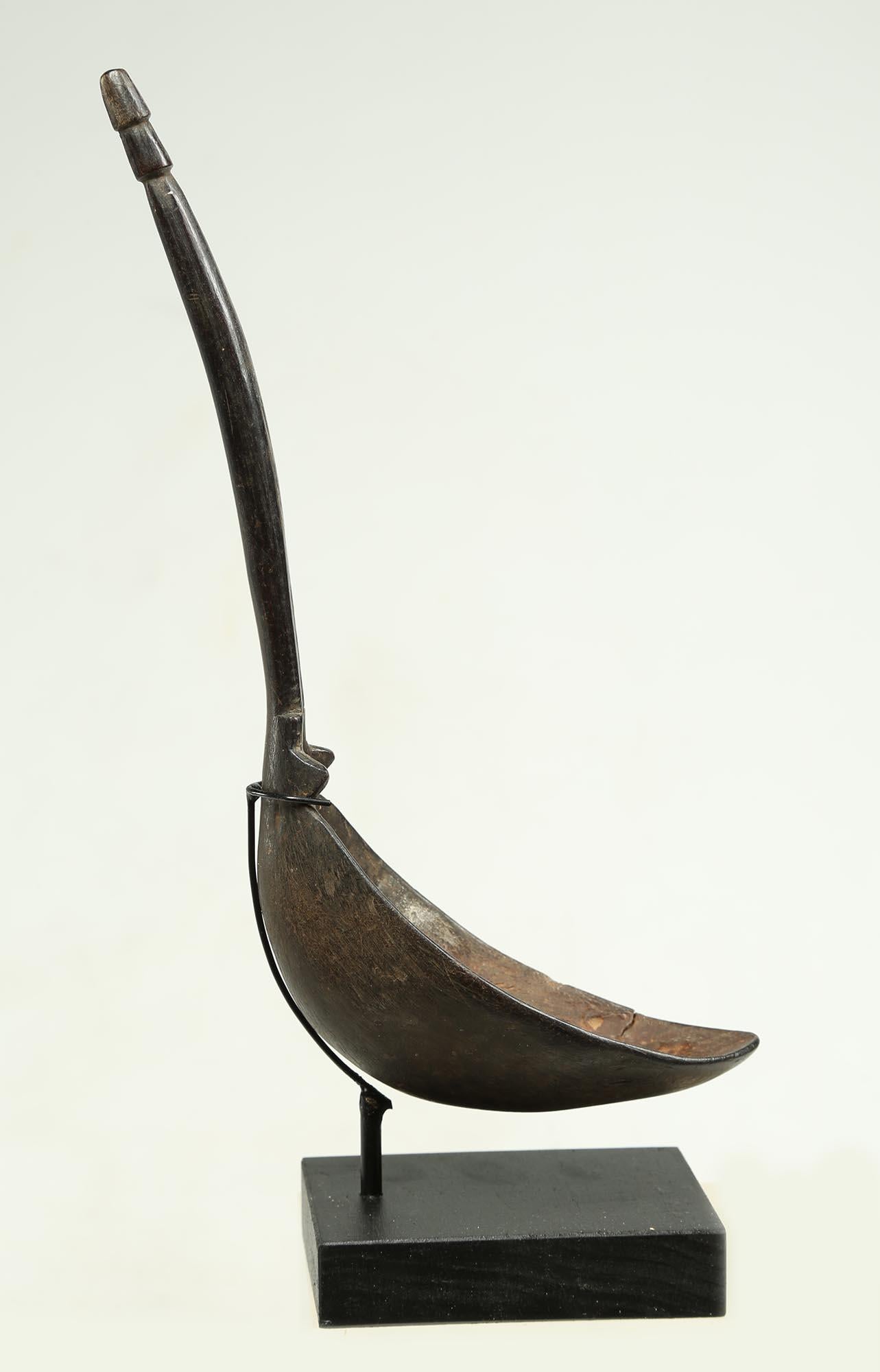 Understated and elegant, ancient Egyptian in feeling, this is a refined Dinka carved wood spoon, South Sudan, Africa, created in the early 20th century, Simple abstract stem-like handle with small projections just above spoon bowl. Old crack on edge