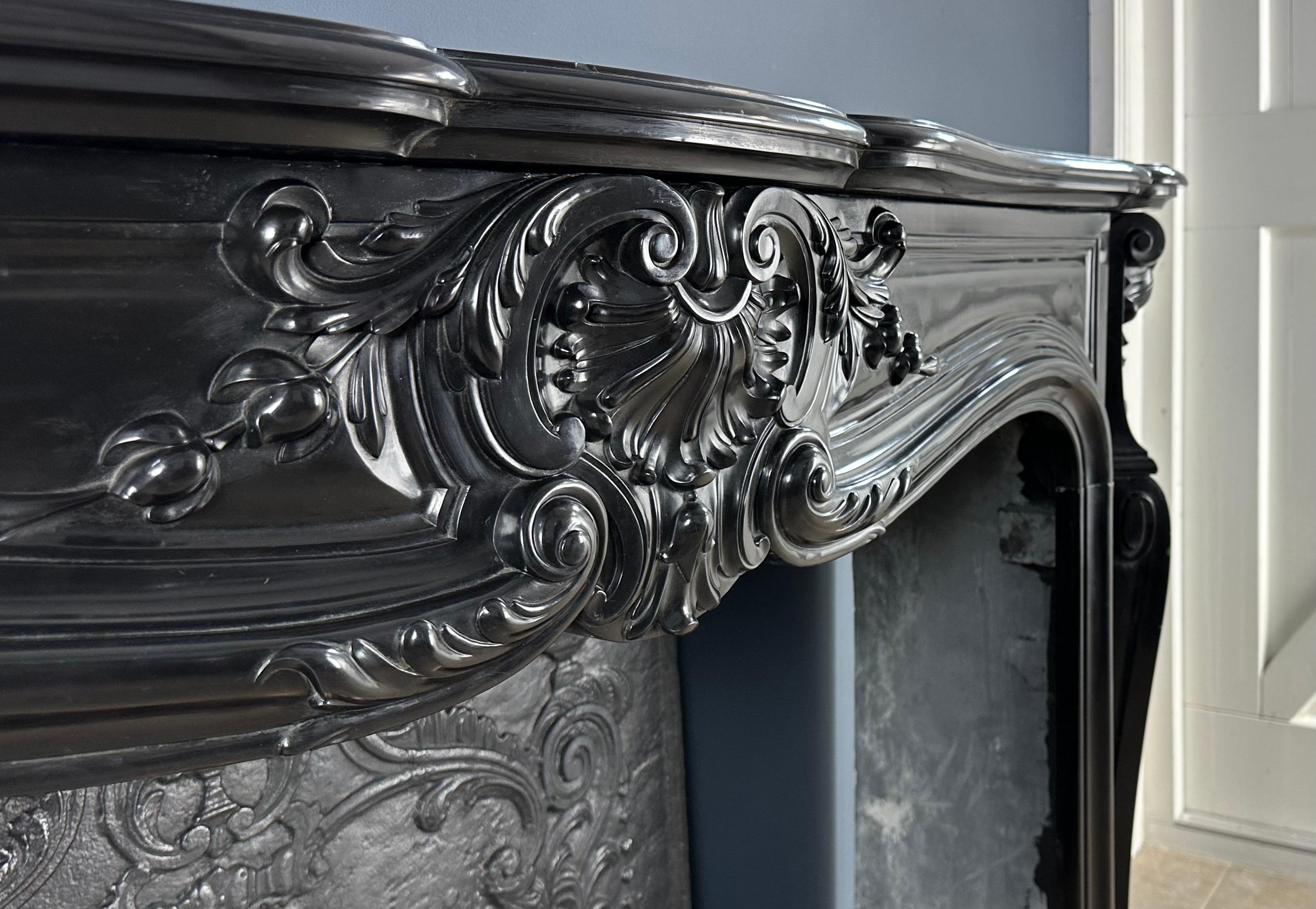 Enter a world of luxury with our unique Louis XV Style Noir de Mazy Antique Marble Front Fireplace. This piece exudes decadence and luxury, and its equal is rare to find. The fireplace is infused with richly detailed ornamentation, including