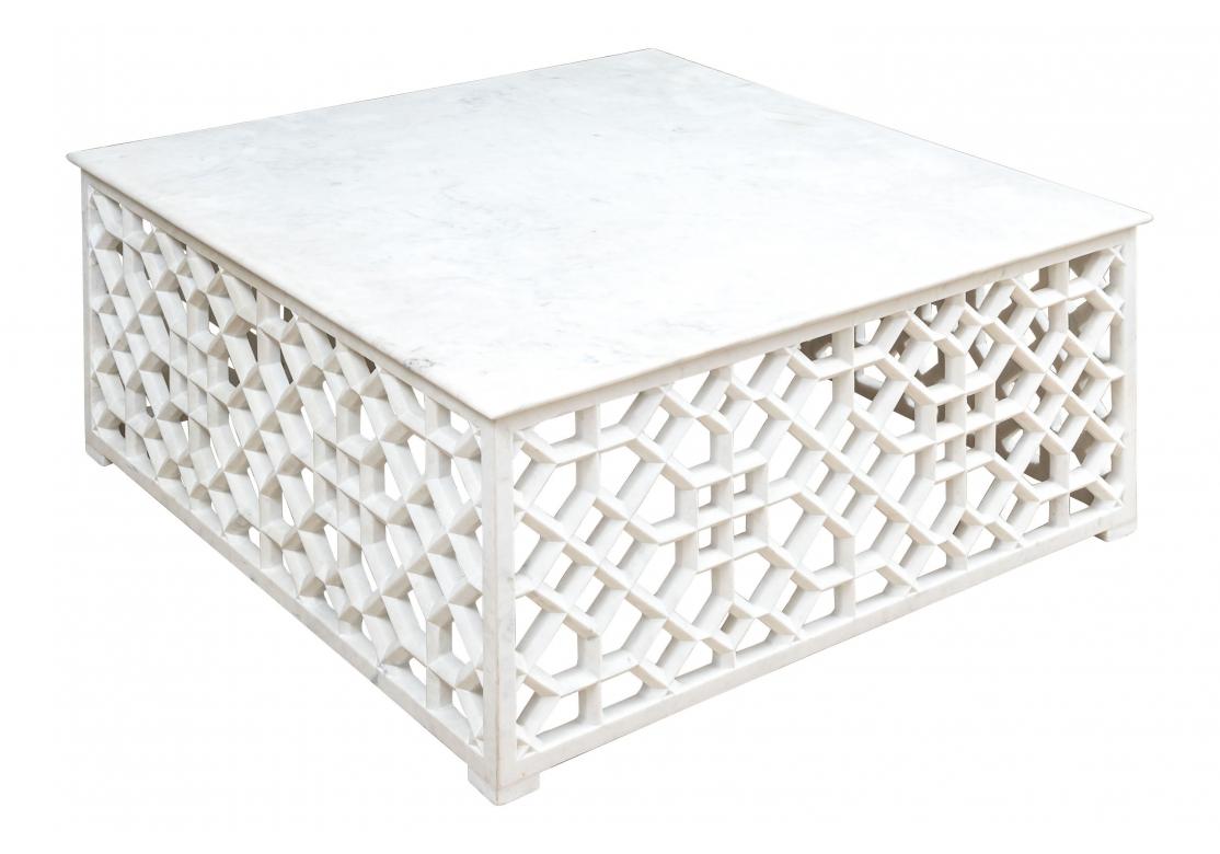 Une table carrée en marbre, élémentaire et fantastique, avec un cadre en marbre percé et un plateau en marbre massif. Le marbre présente des inclusions sombres qui ajoutent de la profondeur à la présentation. L'ensemble de la table est d'une grande