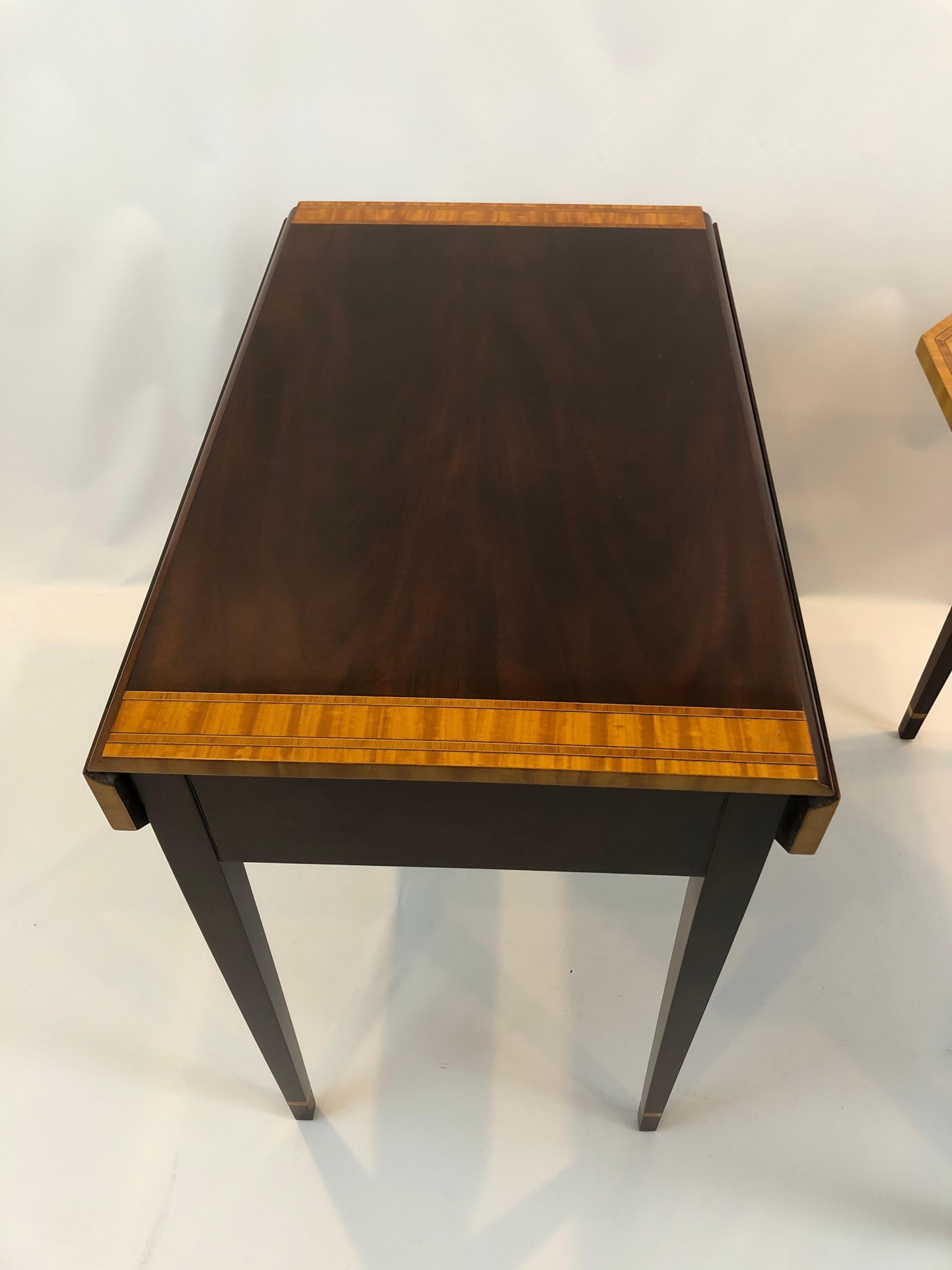 Very elegant classic pair of Pembroke dropleaf mahogany end tables having contrasting satinwood banded inlay around the top, drawers and lovely tapered legs. The bellflower decoration on the legs are Hepplewhite inspired. Single drawers have pretty
