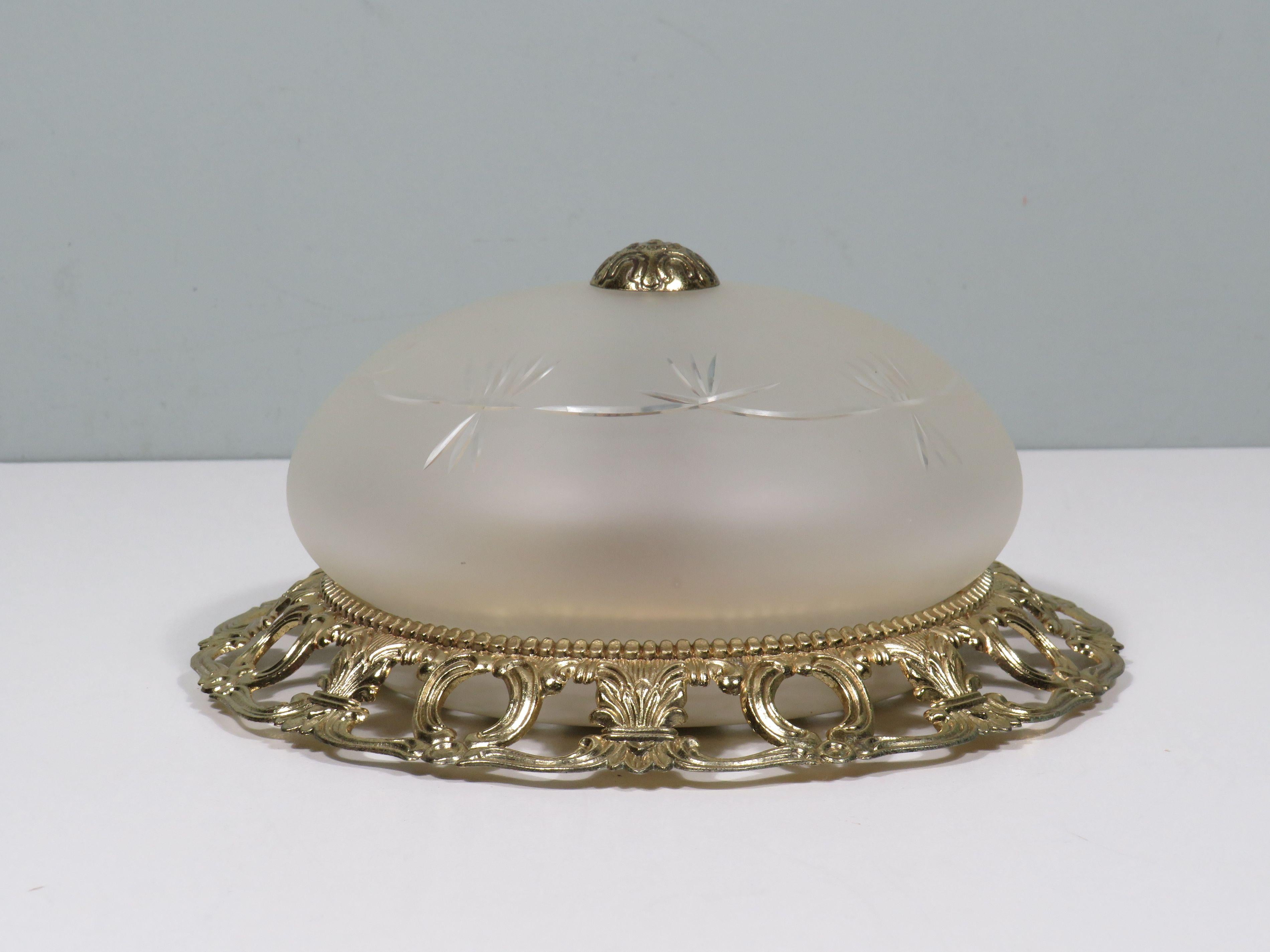 Bring a touch of elegance to your interior with this beautiful ceiling or wall lamp from the period 1960-1970. The white matte glass with cut motifs provides a soft and atmospheric light distribution, while the openwork brass edge and brass cap give