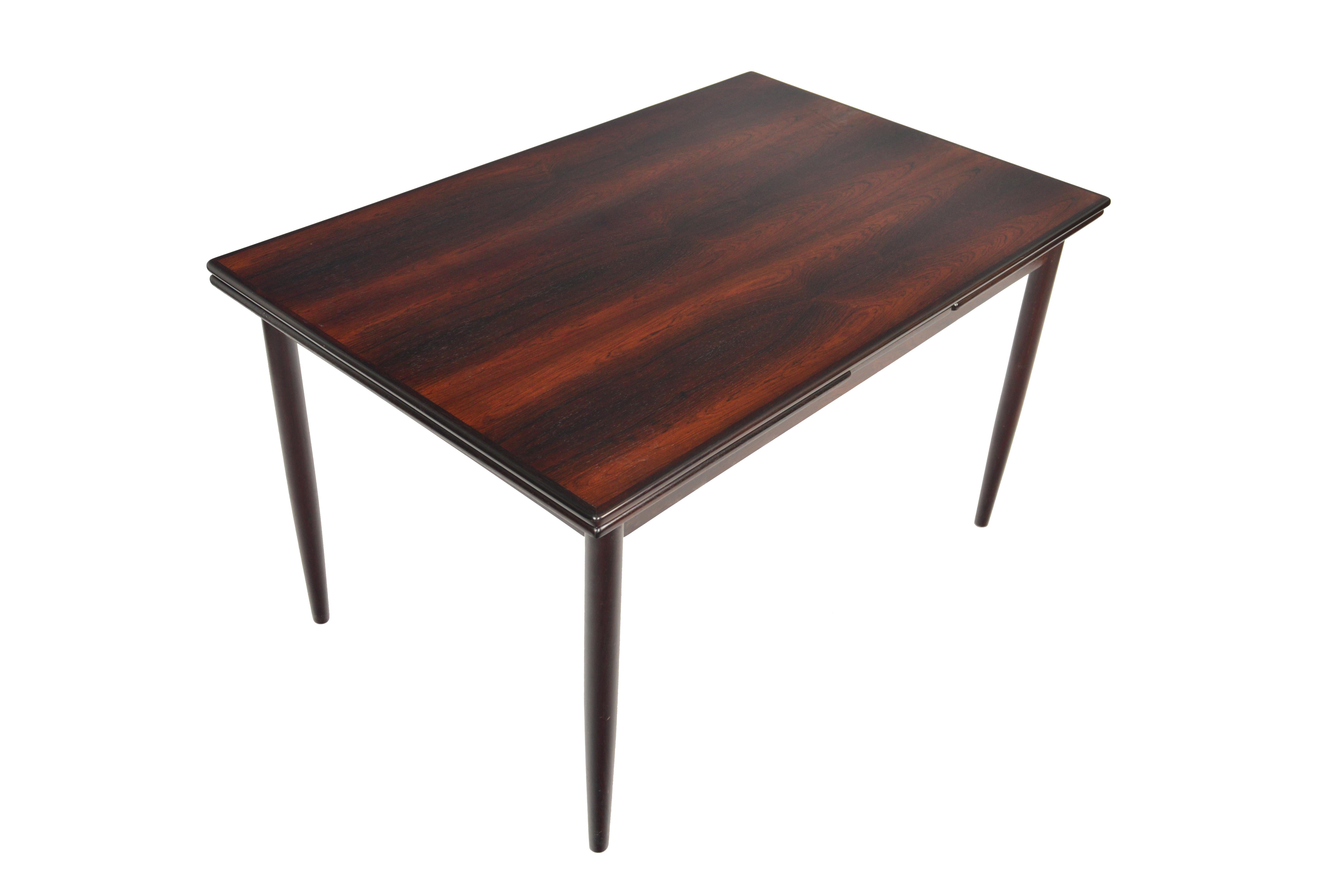 This gorgeous Danish modern Brazilian rosewood dining table offers soft banding and gorgeous wood grain. Two draw leaves pull out to almost double the size of the table for entertaining. Expands to 91