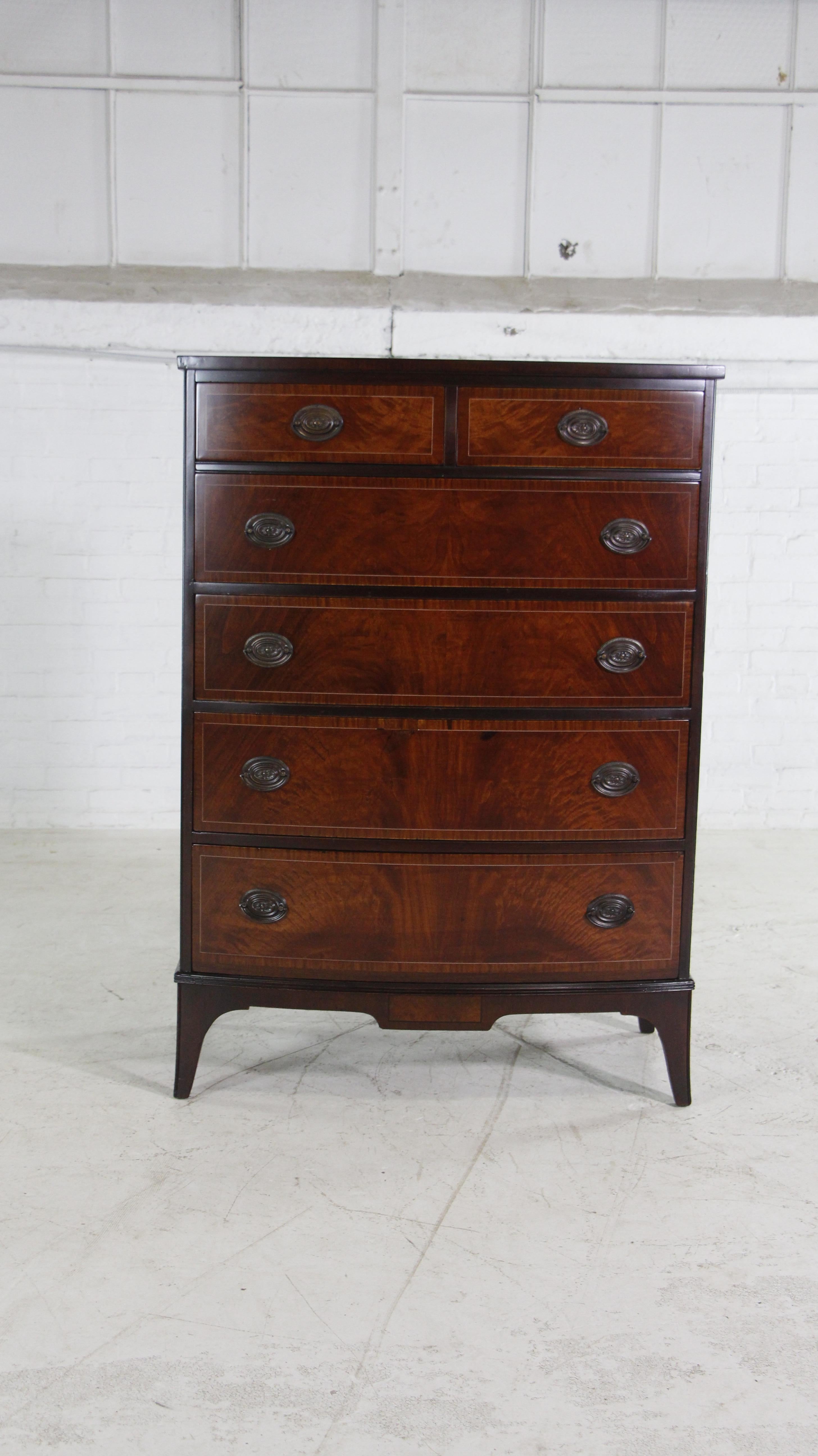 Early 20th century inlaid dark and light tone red mahogany dresser with six dovetail jointed drawers Features the original oval brass hardware. Manufactured by John Stuart Inc., New York.