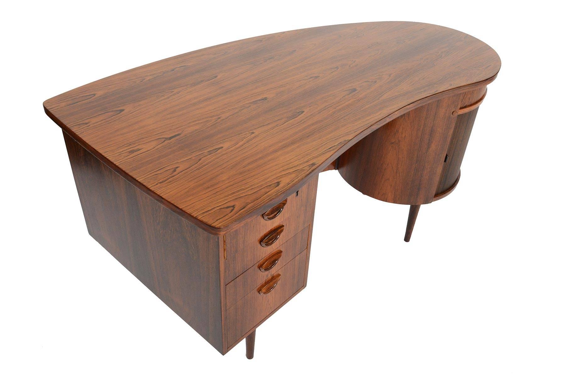 This rare Danish modern model 54 executive desk was designed by Kai Kristiansen for Feldballes Mobelfabrik in the 1960s. Executed in Brazilian rosewood, this desk features a bank of four drawers with Kristiansen's distinctive eyebrow shaped drawer