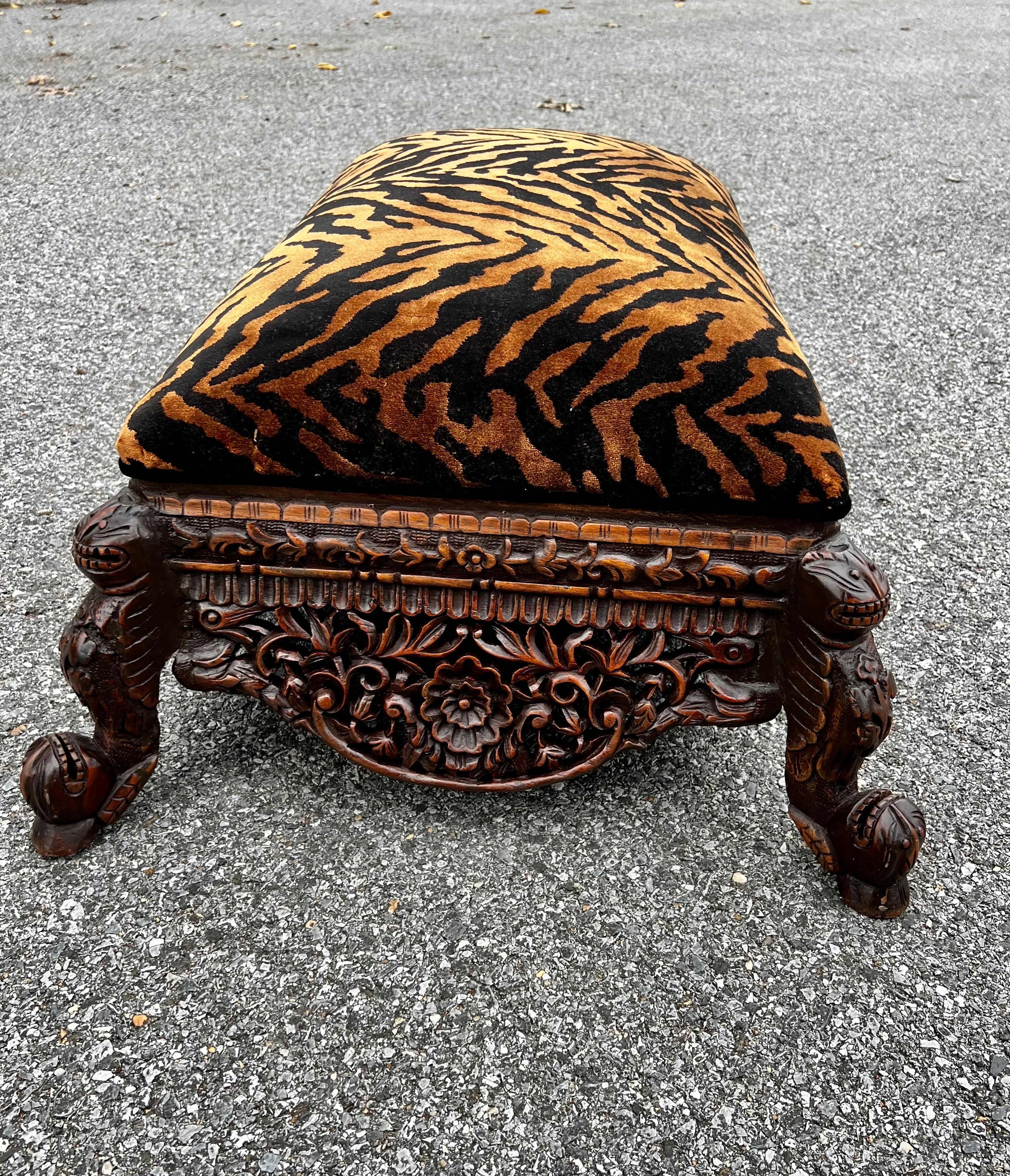 Luxurious late 19th Century Anglo-Indian ottoman heavily carved. Newly reupholstered with a gorgeous tiger fabric with tones of gold with black velvet piping. As you can see in pictures depending how light reflects on the fabric more gold tones are