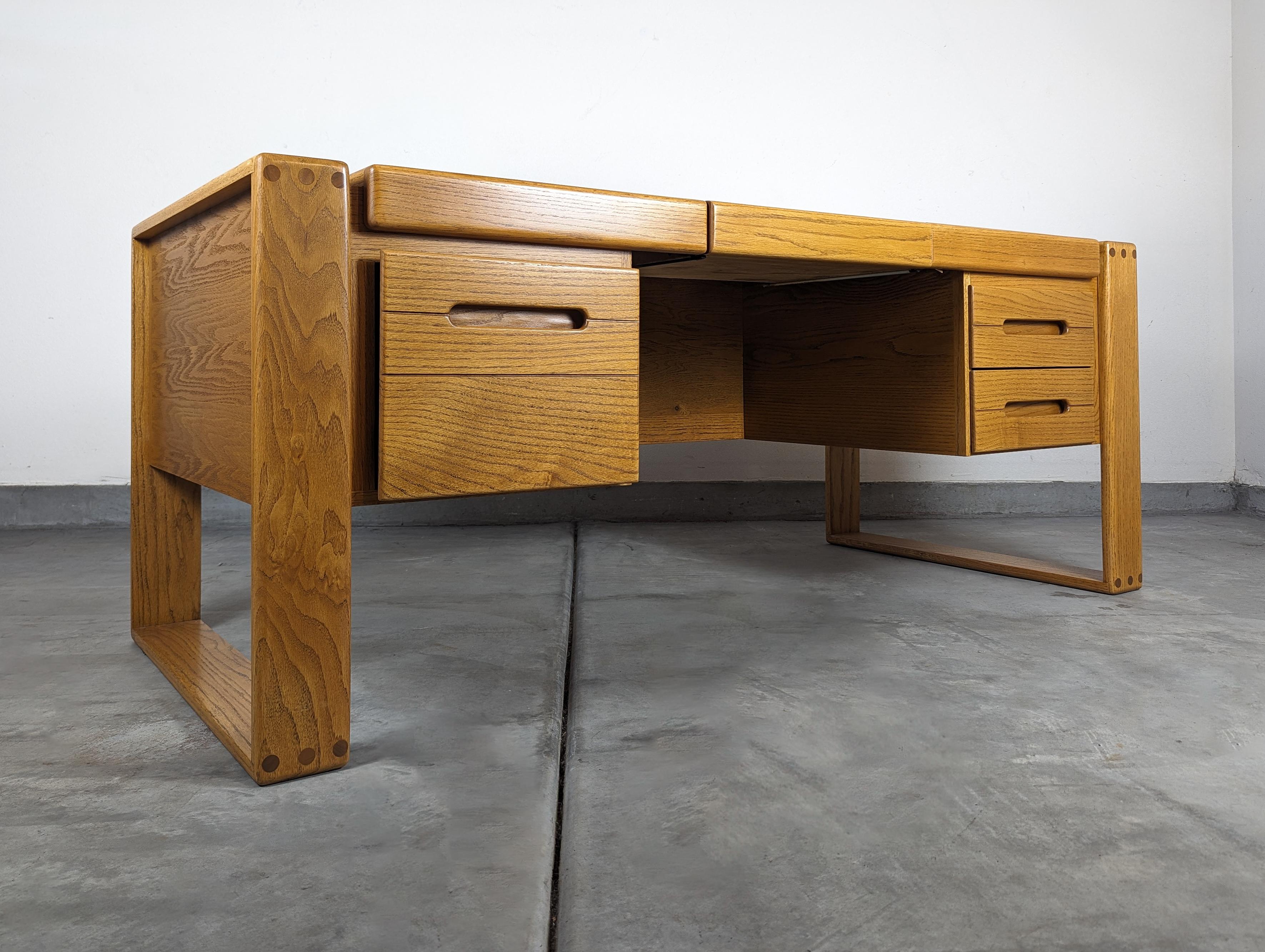 For sale is a stunning, professionally refinished desk designed by the iconic Lou Hodges for the California Design Group in 1981. This piece is a true testament to Hodges' unparalleled craftsmanship and keen sense of functional design.

The desk is