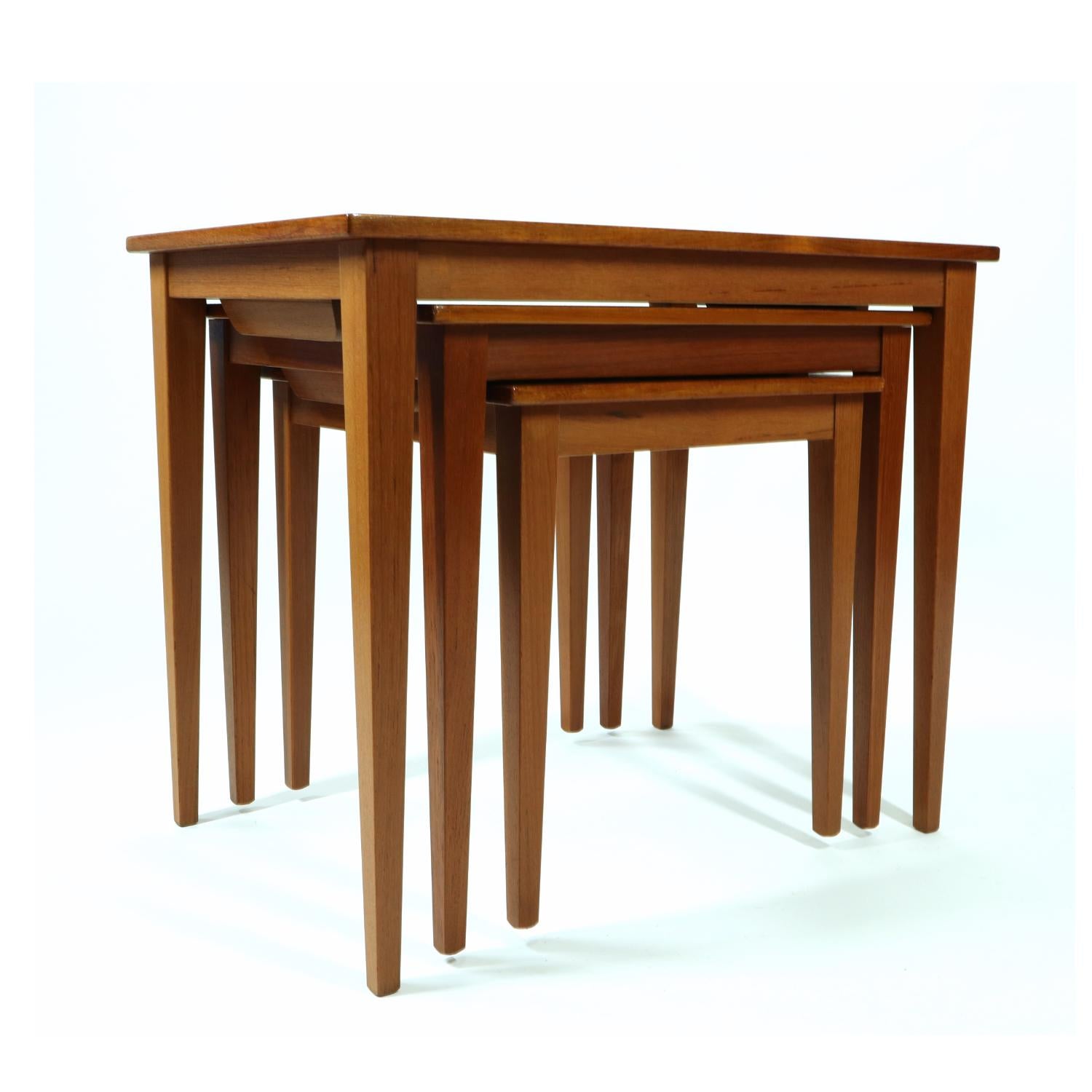 Vintage Mid-Century Modern Danish teak nesting tables, freshly restored. This set of three side tables are unmarked, but exhibit exceptional quality. The set includes three tables of ascending size. Both of the smaller tables nest within each other