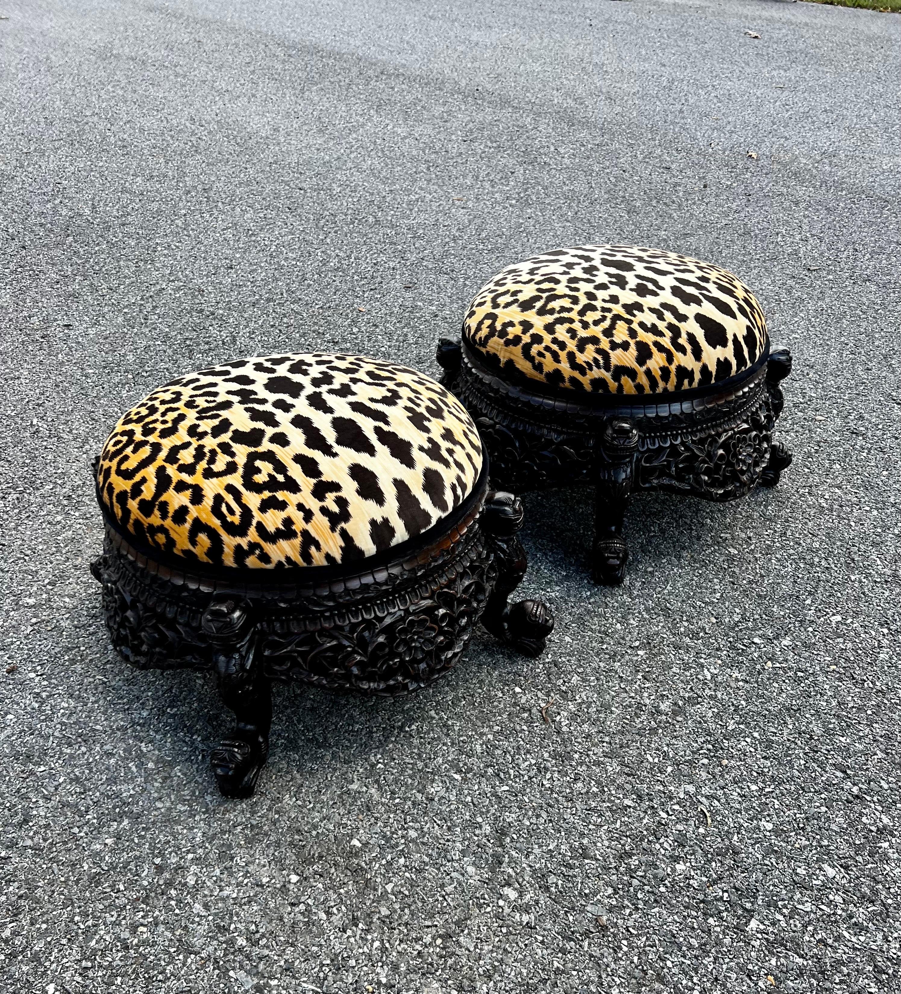 Luxurious late 19th Century Anglo-Indian ottoman heavily carved. Newly reupholstered with a gorgeous cheetah fabric with black velvet piping. The colors and lighting on the fabric is the perfect contrast to the dark wood frame.    
These ottomans