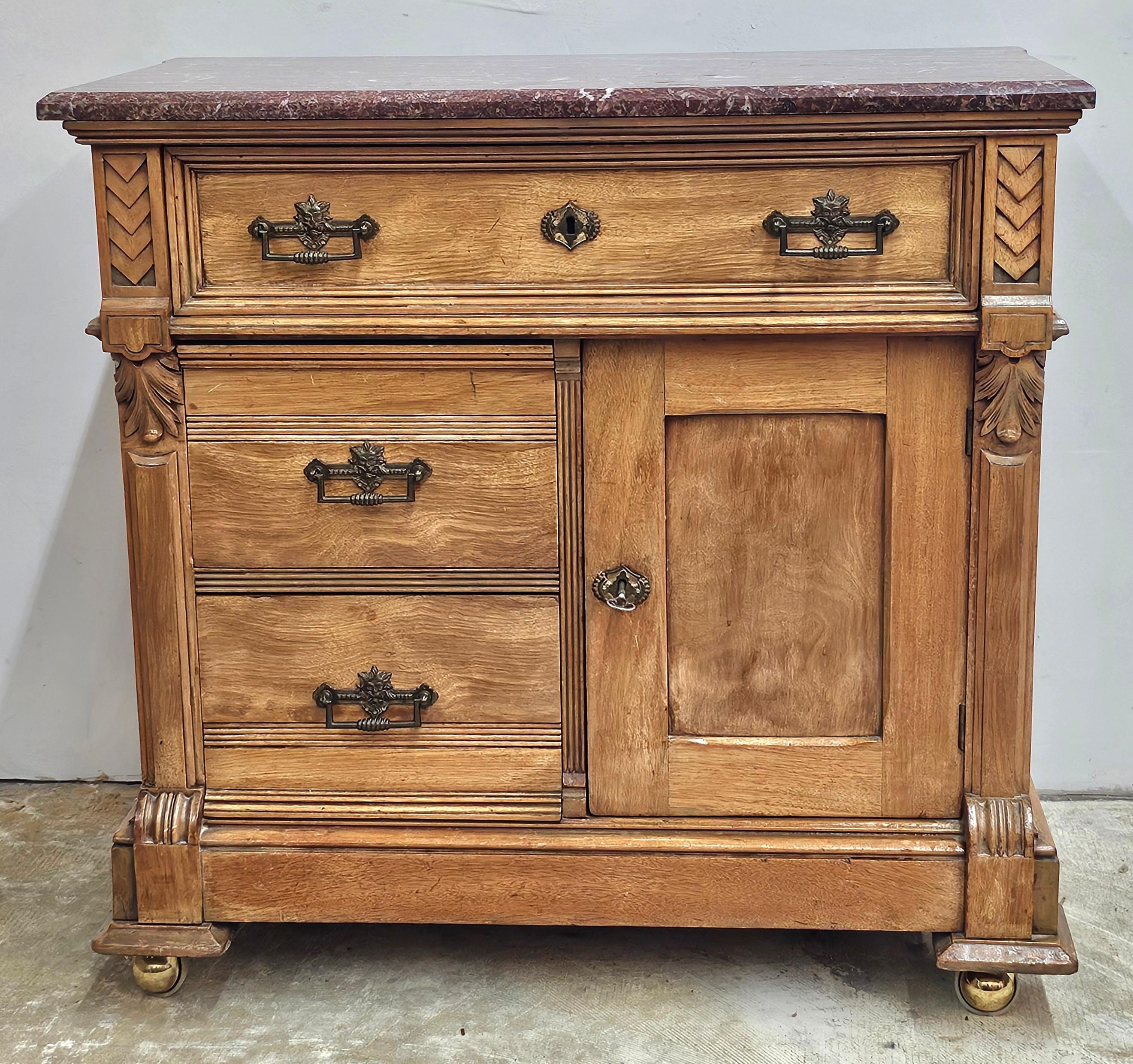 Un armario rodante de estilo renacentista victoriano con tapa de madera de frutal y mármol marron. Gran estado antiguo con cerraduras funcionales y llave para el cajón superior y el armario de la puerta inferior. Cajones de funcionamiento impecable.