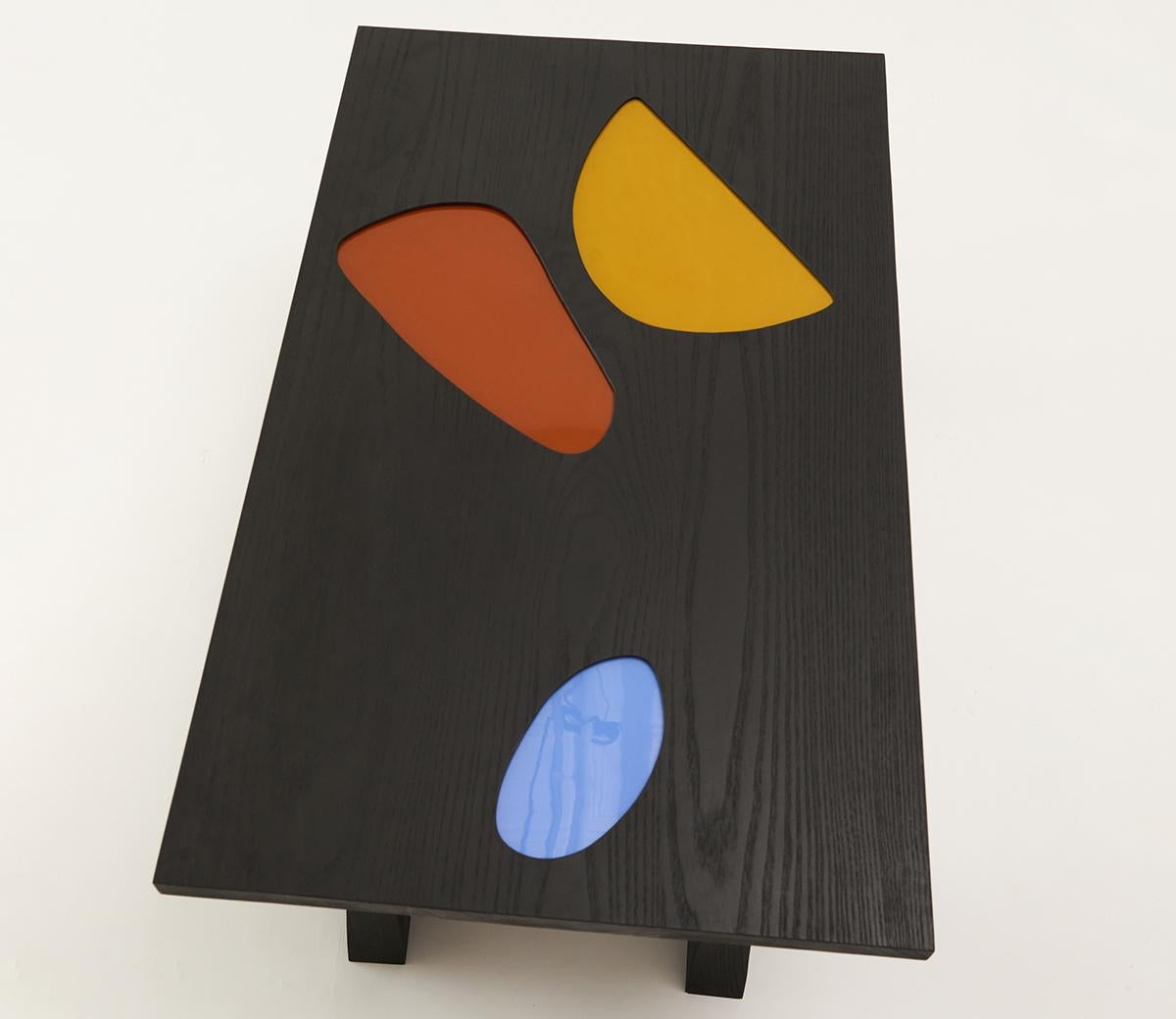 In the Reflection coffee table, abstract colored pools of opalescent and transparent stained glass are inlaid into the surface of the table top, creating soft ripples of color as sunlight and shadow move within the space. This piece pays homage to