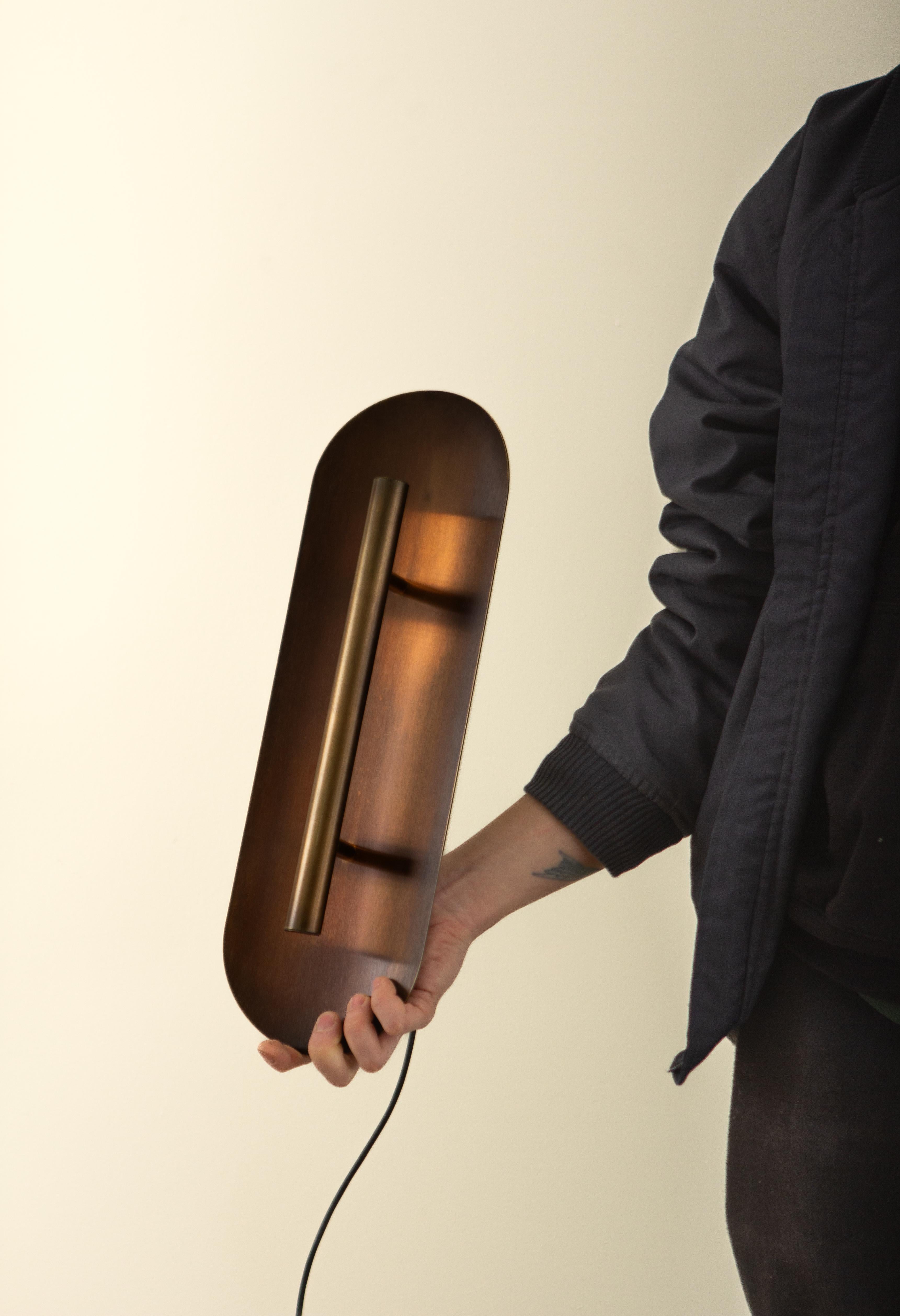 A powerful LED light source reflects off a delicately curved dish, accenting a room with a soft indirect light.  
The in-studio patina bronze features a deep, chocolatey finish, adding a sense of earthy warmth to any interior. 

Two sizes are