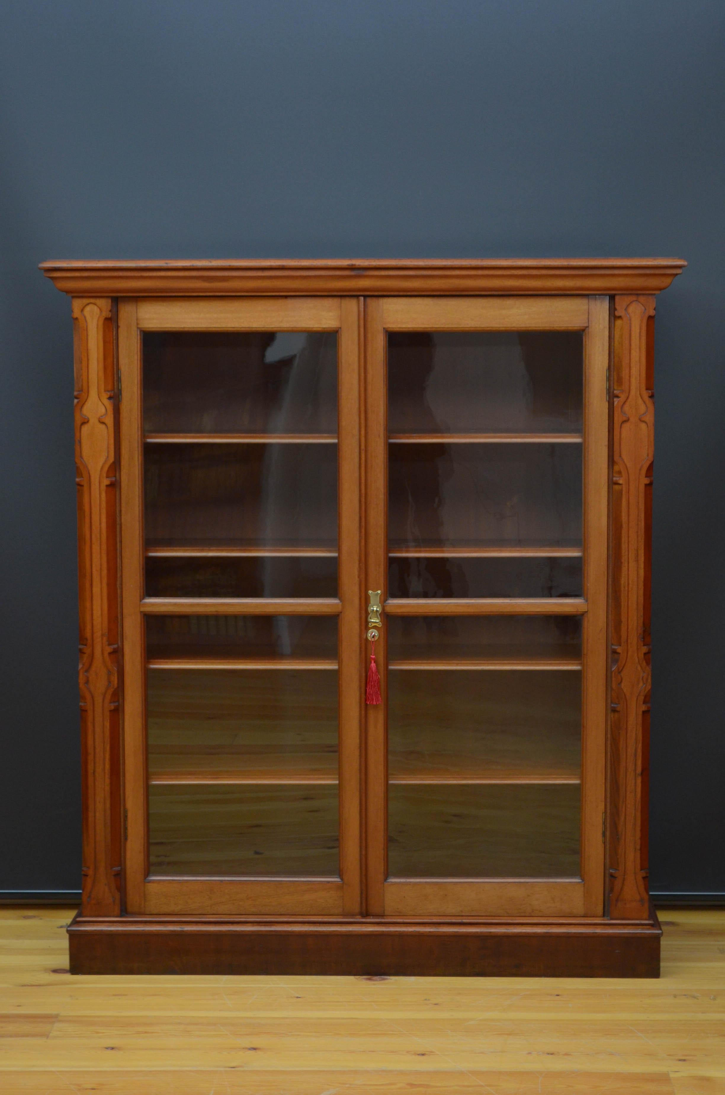 S02 stylish Victorian glazed bookcase in mahogany, having oversailing top above a pair of glazed doors fitted with working lock and a key and enclosing four height adjustable shelves, all flanked by shaped uprights, standing on moulded plinth base.