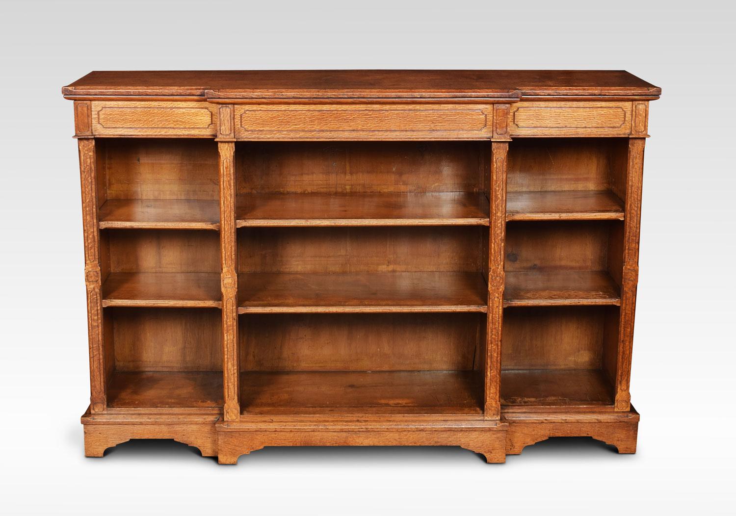 Reformed Gothic oak open breakfront bookcase, the large rectangular top with moulded edge above three frieze drawers and three bays of adjustable shelves divided by chamfered stop columns with similar detail on the shelves. All raised up on plinth