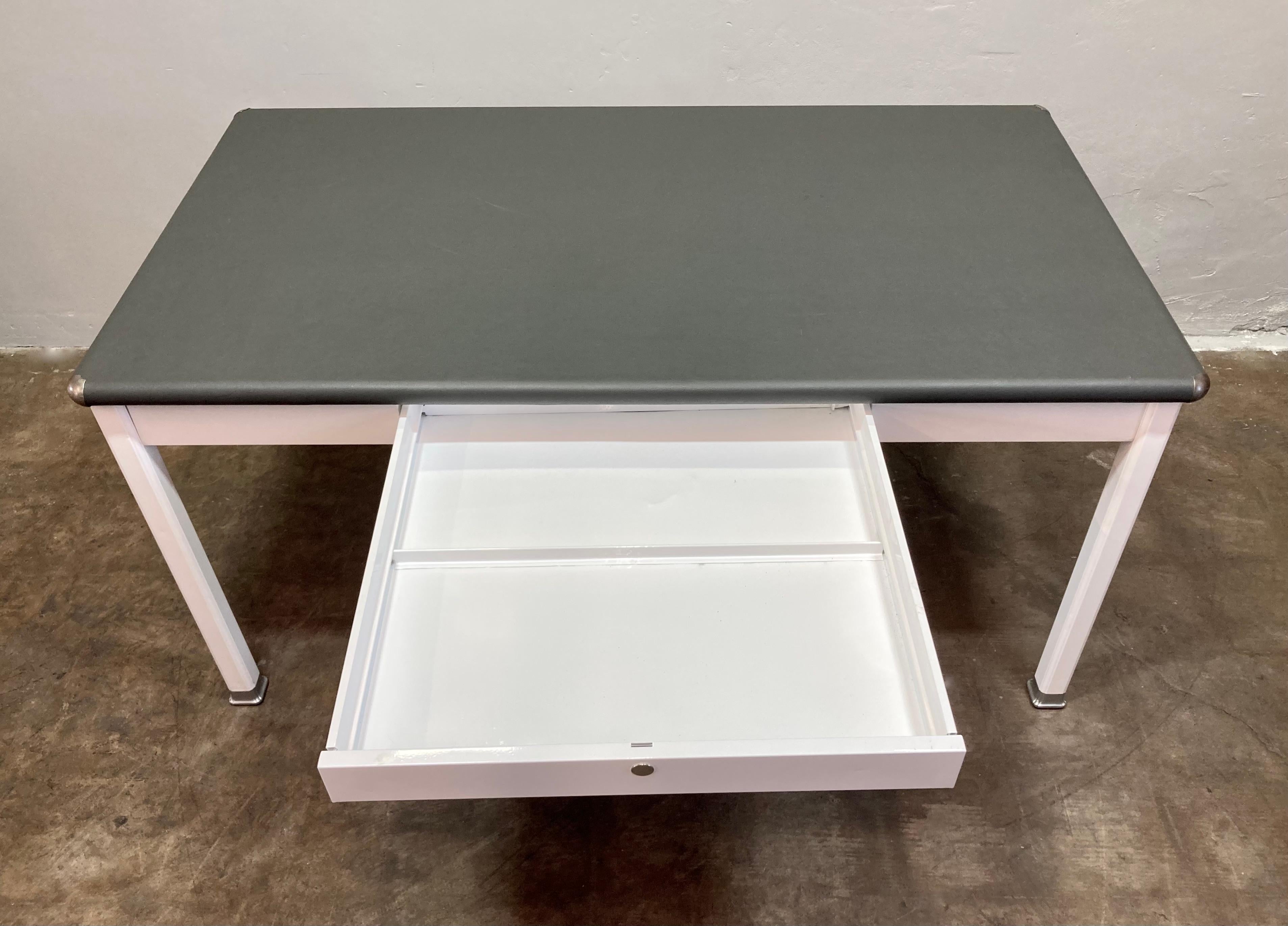 Fantastic condition 1920s Shaw Walker 4 Leg table. Refurbished steel table base has been freshly powder-coated in gloss white (WH-12) and has a grey vinyl top. Large pull-out drawer in the center front of the table frame. Table-top also has new