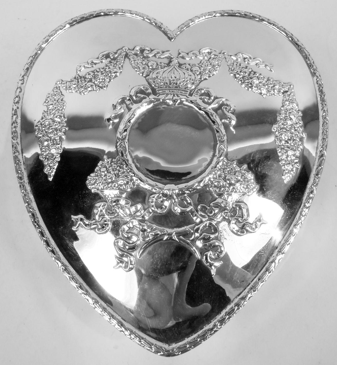 American Edwardian Classical sterling silver jewelry box, ca 1900. Heart-shaped with hinged cover. Ornament includes garlands and ribbon applied to sides and cover and well as three cartouches in crown and cornucopia surrounds. Regal and romantic.