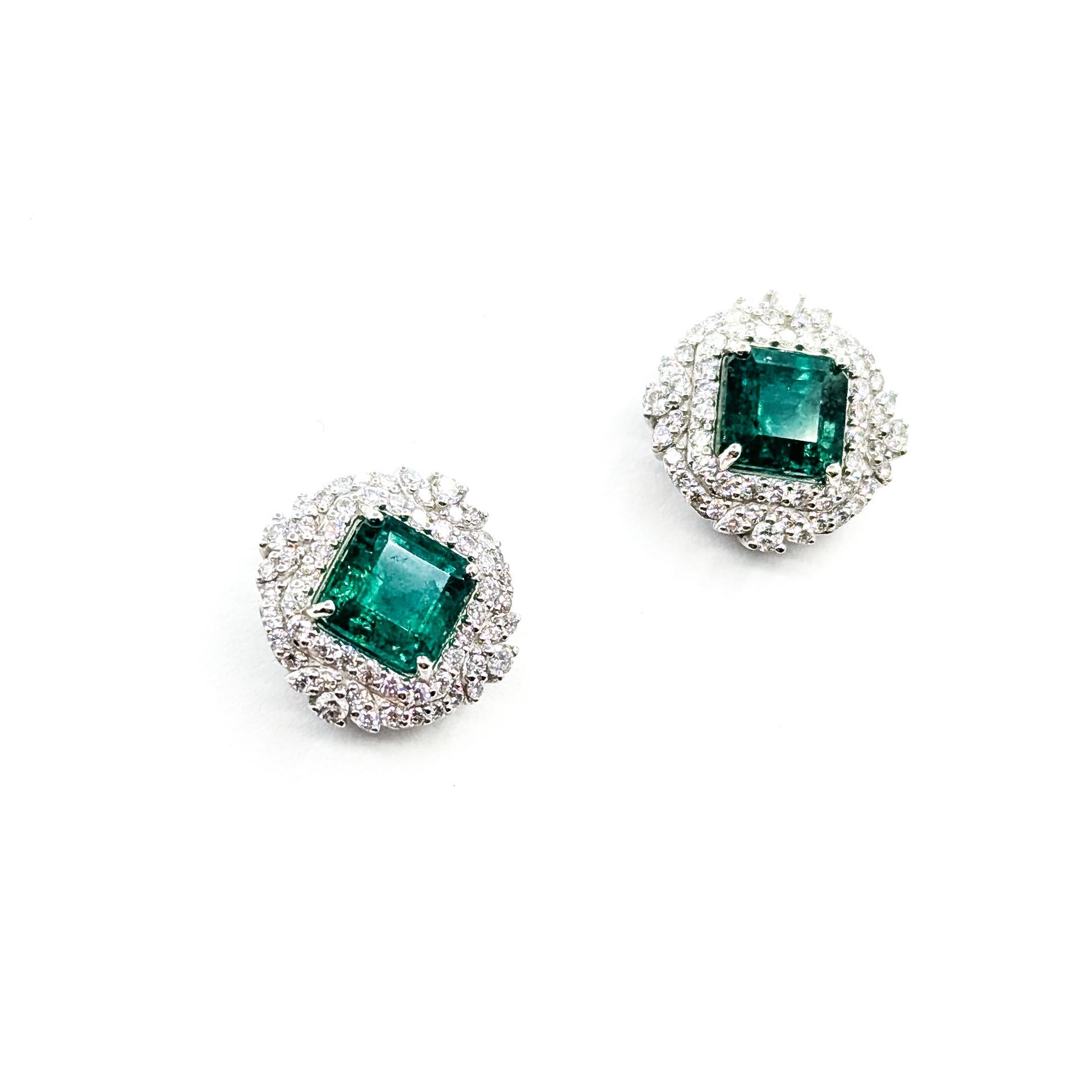 Ces luxueuses boucles d'oreilles sont fabriquées en platine et présentent de vives émeraudes serties encadrées par un double halo de diamants ronds étincelants. Les émeraudes pèsent ensemble 3,62 carats, tandis que les diamants presque incolores