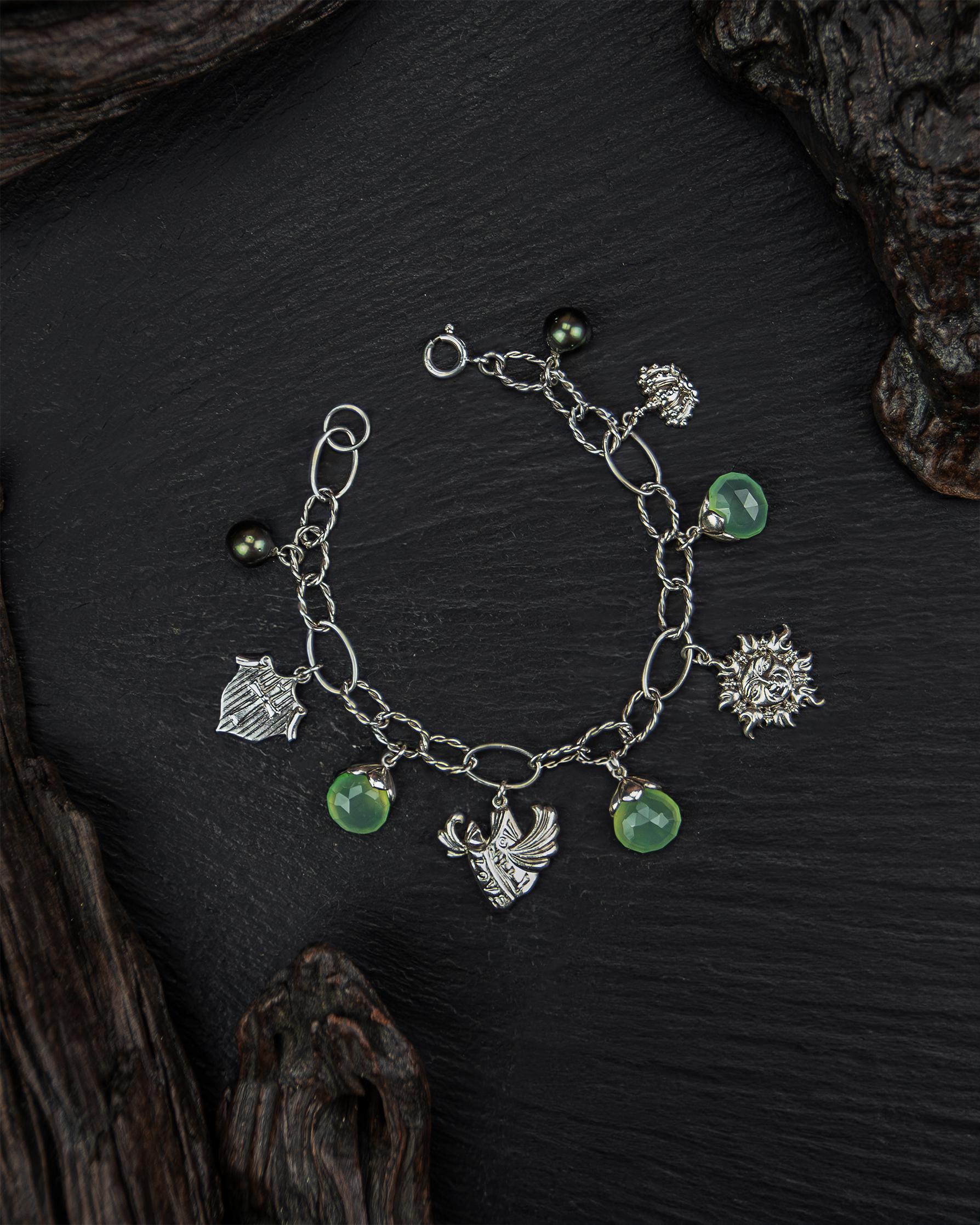 Live up your inner magical fantasy with the Regal Fantasy Charm Bracelet, crafted from Sterling Silver, Green Chalcedony, and peacock-colour Tahitian Pearls. The array of charms - a regal crest, love book, smiling sun, and crown - will bring a touch