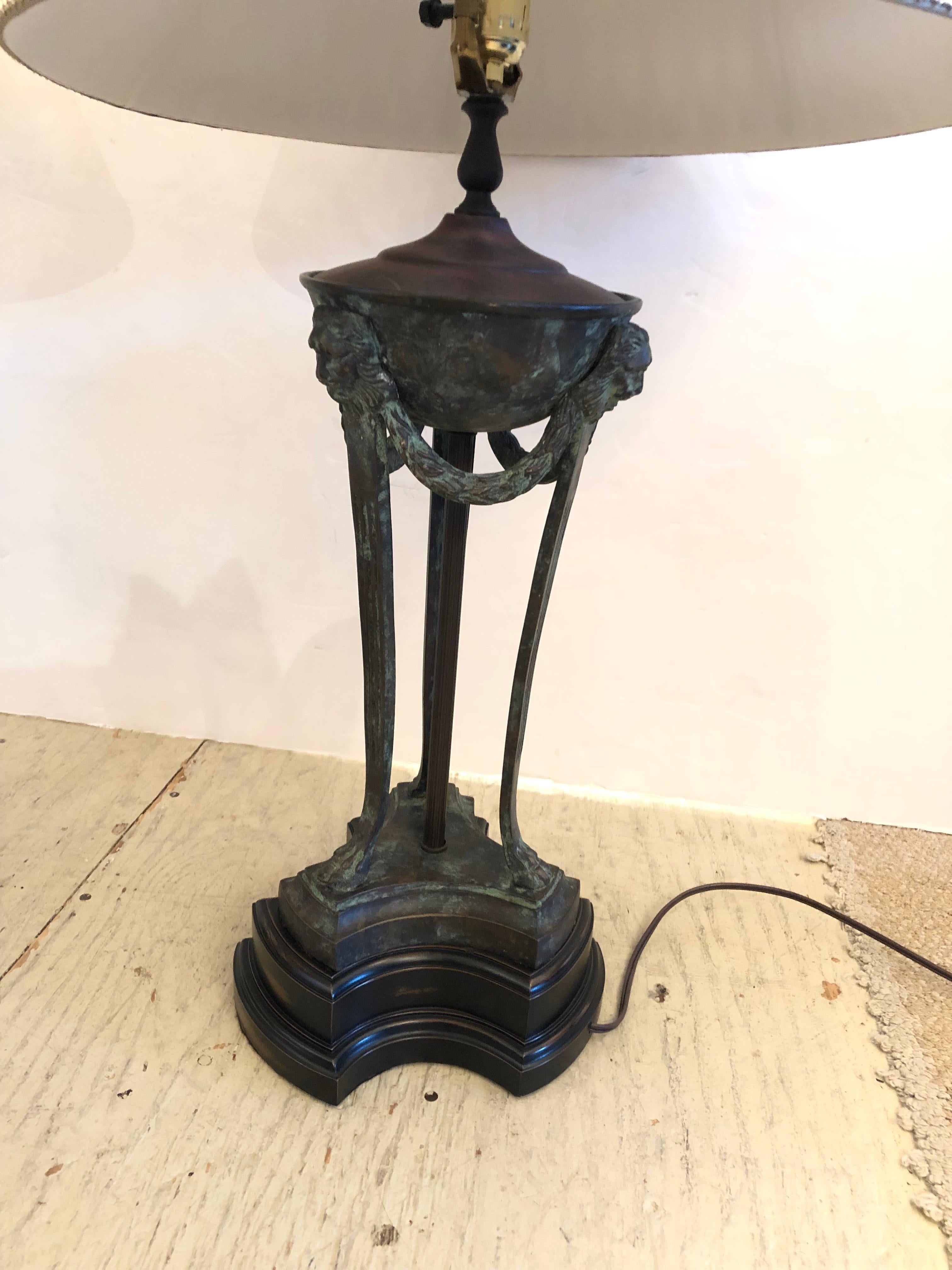 Fancy and elegant pair of neoclassical table lamps having bronze swags, lions heads and paw feet with verdigris patina on a black base. Custom shades are equally impressive having ornate pleats and X decoration around the bottom periphery.
Base is