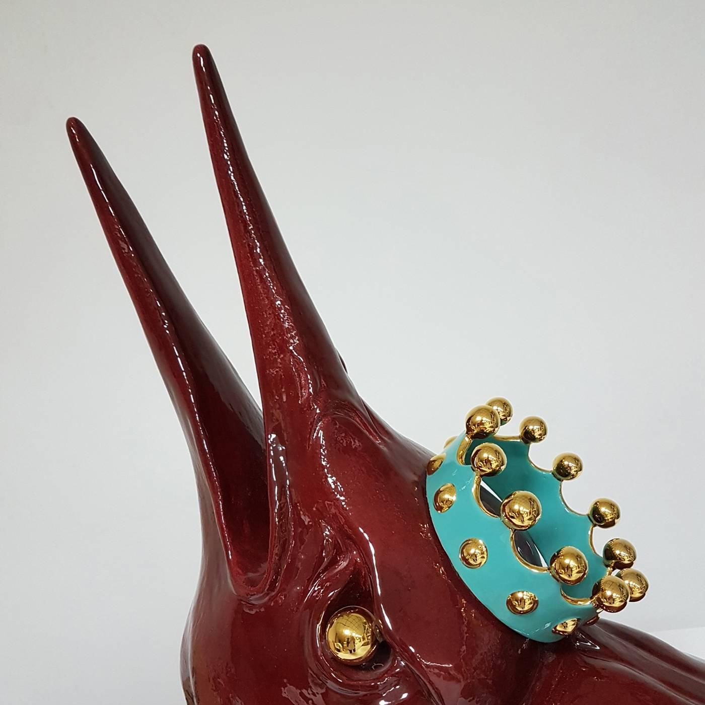 This remarkable piece, made using a mold and handcrafted with the pinch method, has the shape of a bird bust in glossy Sienna finish with a turquoise and gold crown. The striking texture and metallic glare are obtained with an exclusive technique
