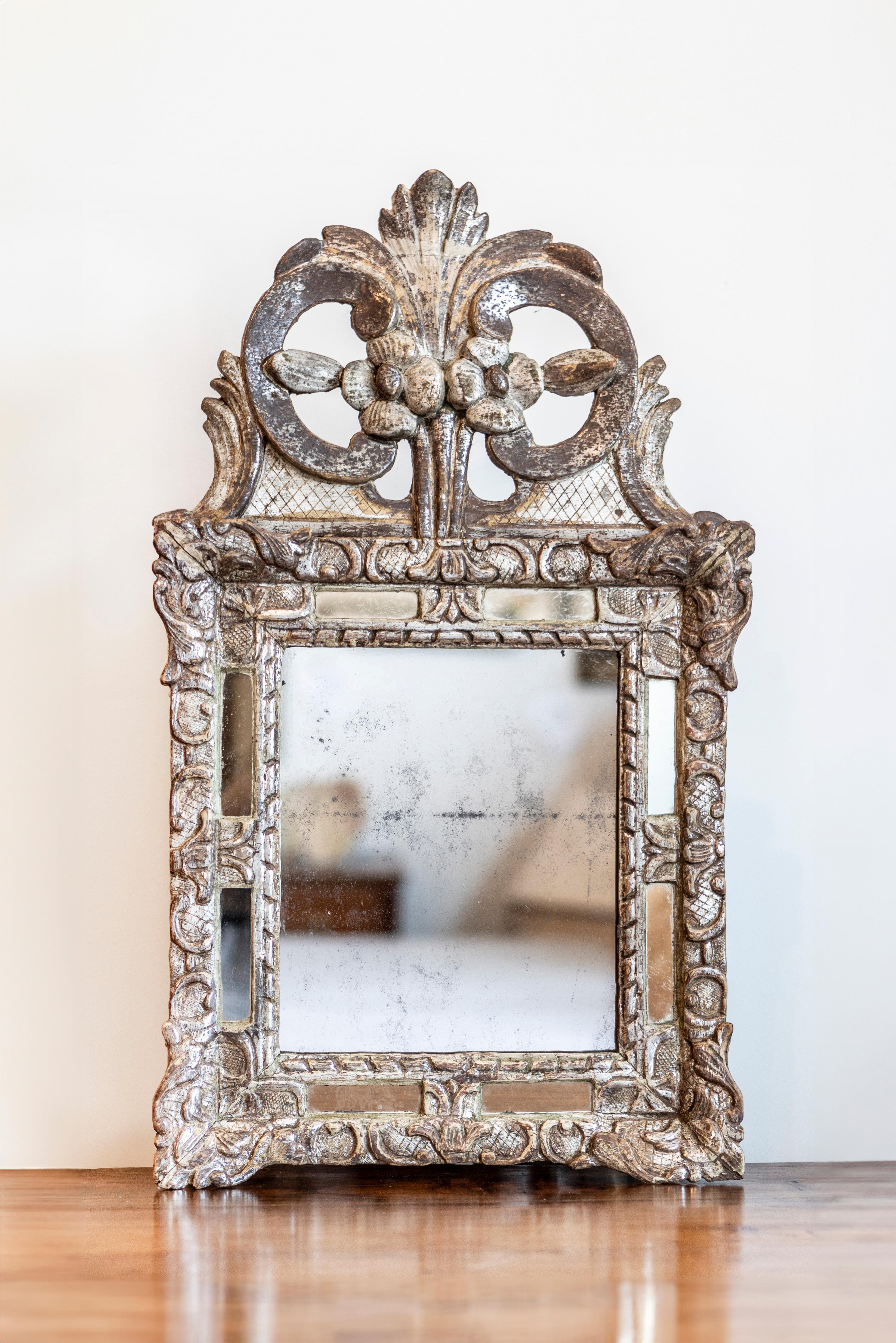 A French Régence period silver parcel gilt mirror with carved floral crest. This exquisite French Régence period silver parcel gilt mirror is a testament to the elegant transitional style that bridges the grandeur of Louis XIV designs with the