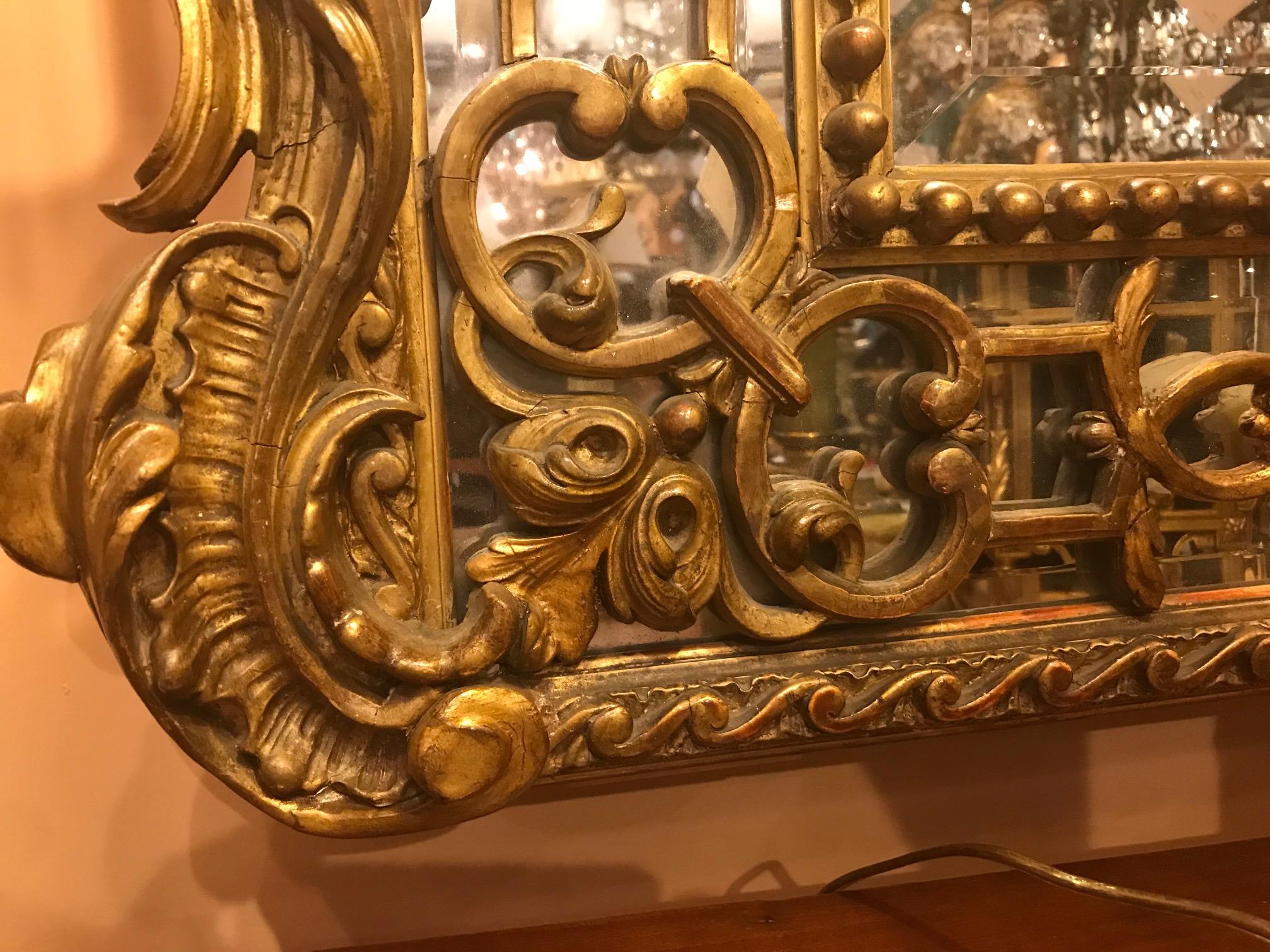 This highly decorative large mirror has a carved central crested pediment flanked by griffins. The open mirrored side panels, combined with the large central shaped plate give a great deal of reflective light. The slender panels of mirrored glass