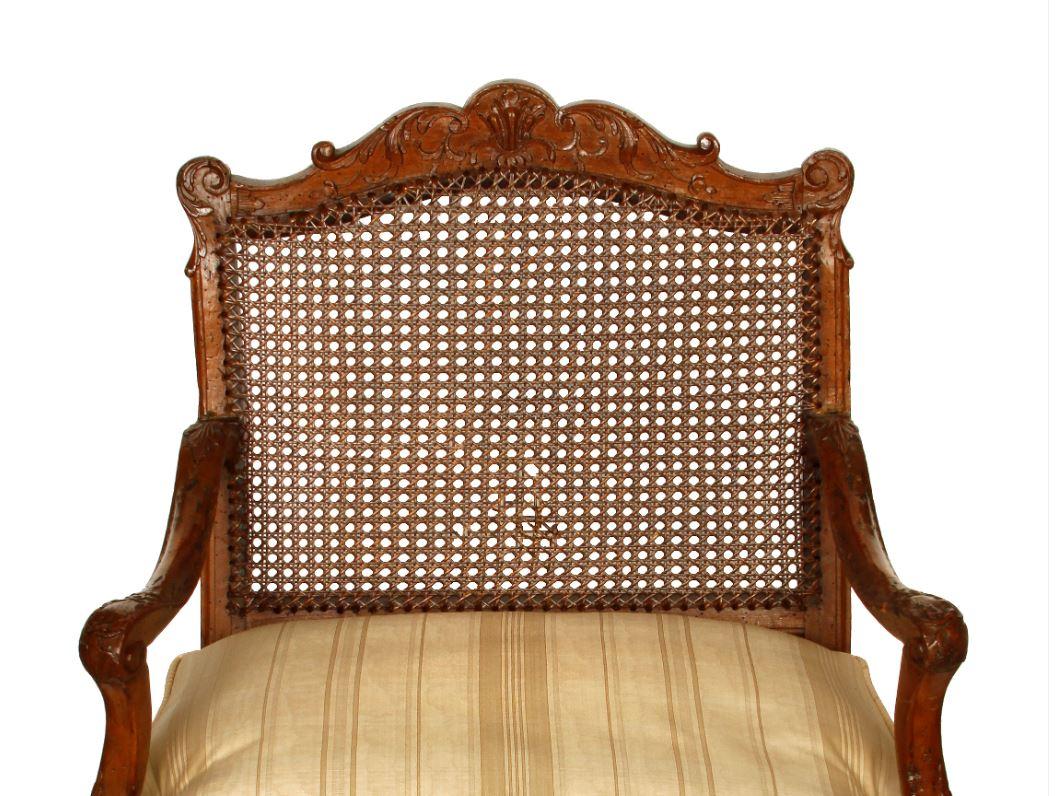 Regence style walnut fauteuil caned seat and back with cushion.