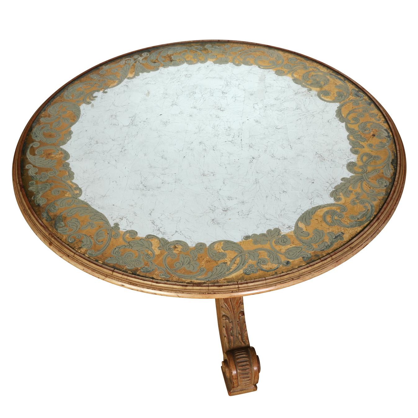 A Regence style round cocktail table with decorated eglomise mirror inset top and three leg base with carved and scrolled legs