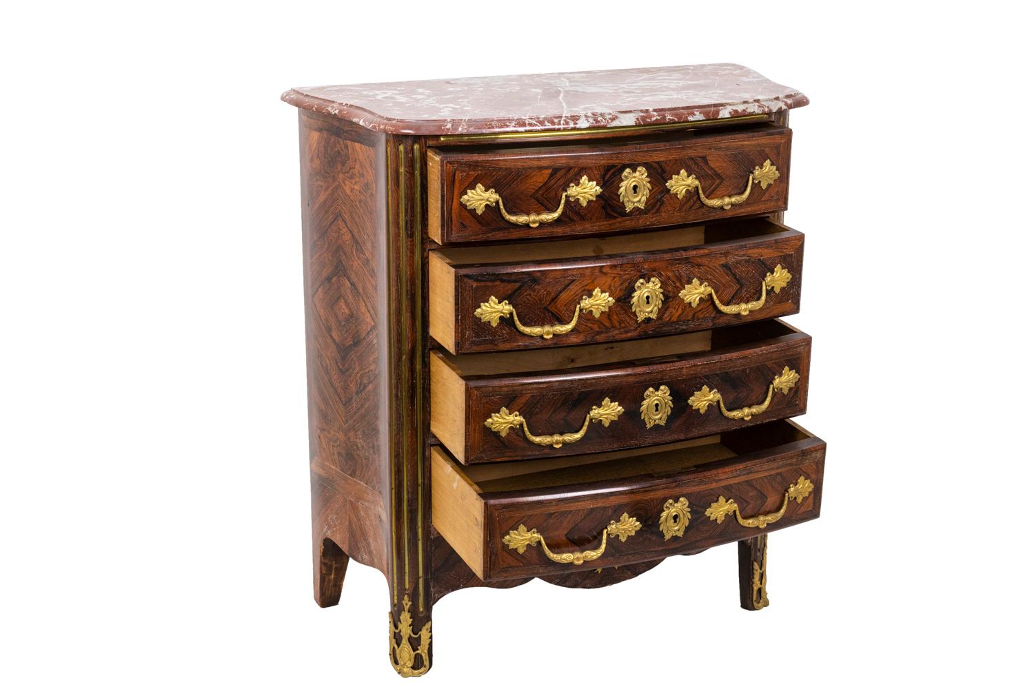 Tiny Regence style commode in kingwood marquetry opening by four drawers on four levels with a crossbar and standing on four straight legs. Bulged shape and scalopped apron. Gilt bronzes ornamentation on handles, escutcheons, inferior crossbar and