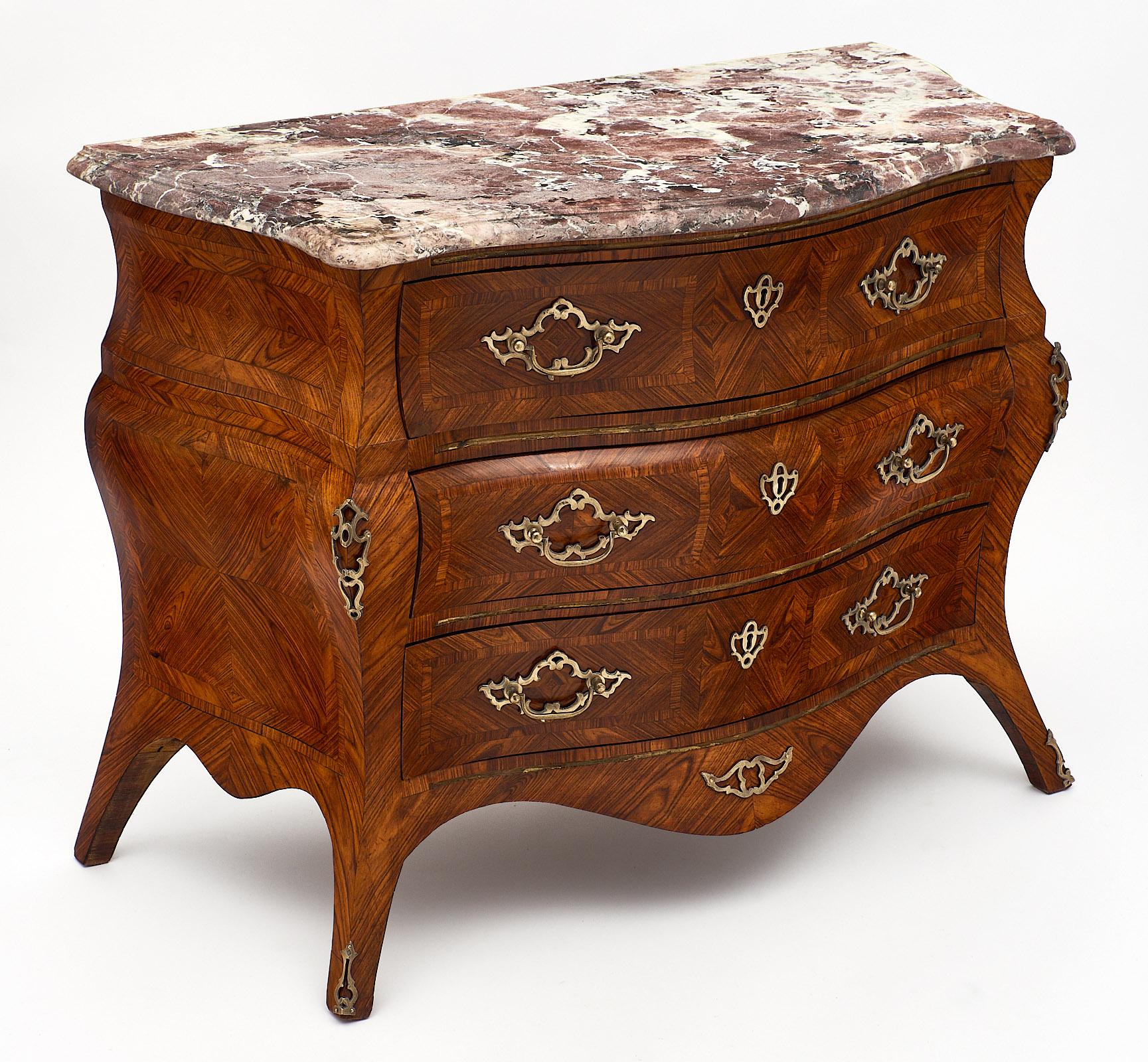 French Régence style chest of drawers with original Rouge Royal marble top. We love the serpentine shape of this piece with convex and concave curves on the sides and drawers. It is made of rosewood with tinted rosewood parquetry. The hardware is