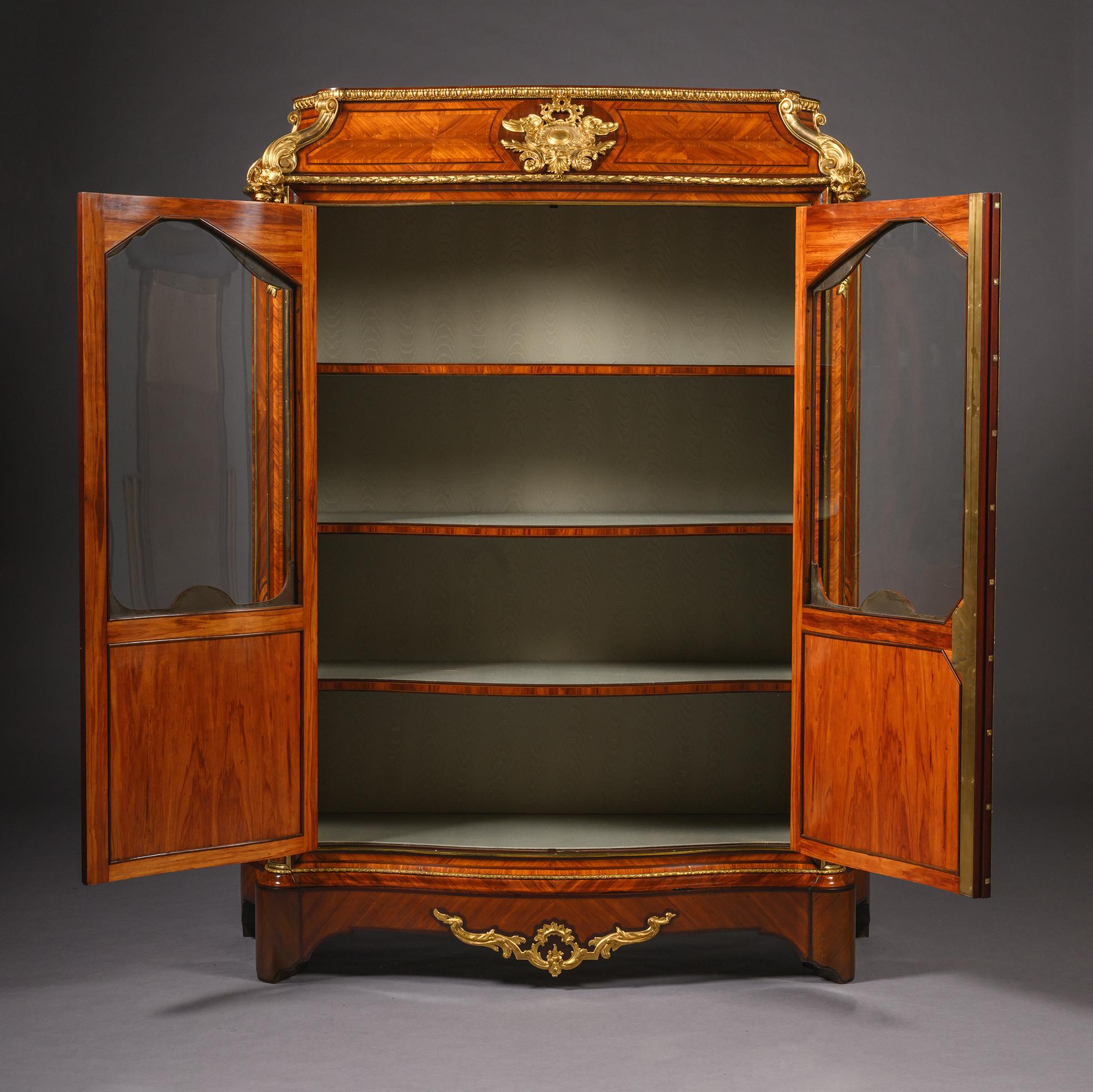 Une superbe bibliothèque ancienne française de style Régence par la Maison Beurdeley, Paris, plaquée en parquet complexe et somptueusement ornée de montures en bronze doré. L'élégant fronton en forme de 