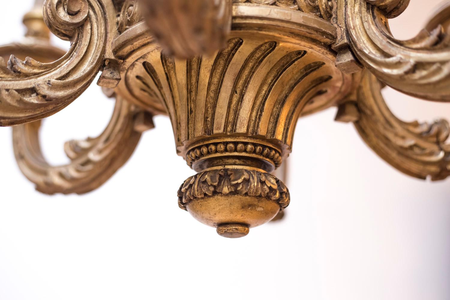 Regence style giltwood chandelier with six arm lights.
Central structure decorated with a frieze of grooves, acanthus leaves, water leaves, tracery, beads, and laurel wreaths. The upper part is adorned with swirls.
The six arm lights are acanthus