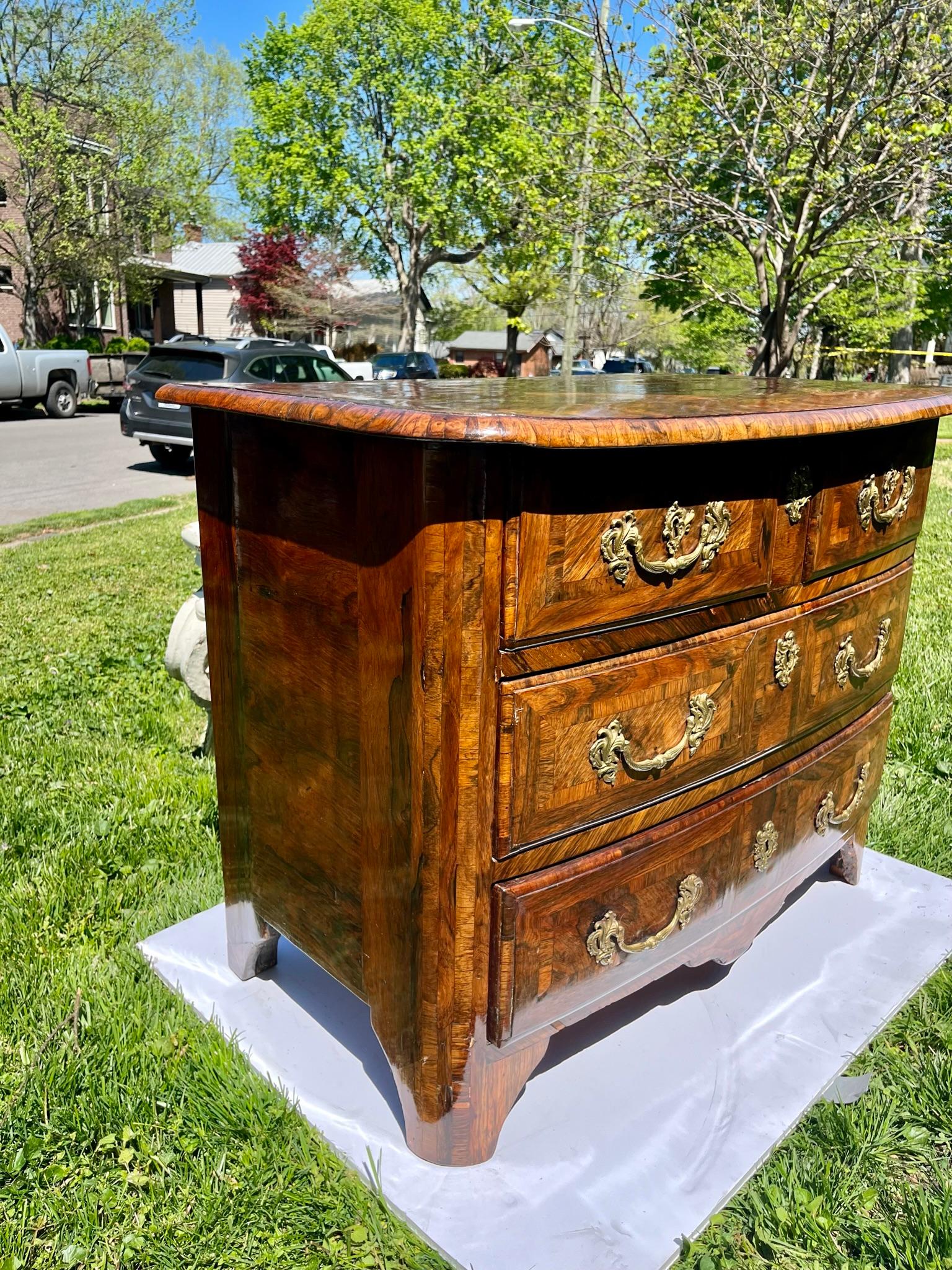 With inlaid parquetry top and parquetry inlaid front corner stiles. Very pretty patina and polish. Perfect bed size chest. 
The front façade in a shallow bow typical of Regence style with rounded front corners . Secondary (drawer sides etc. ) wood
