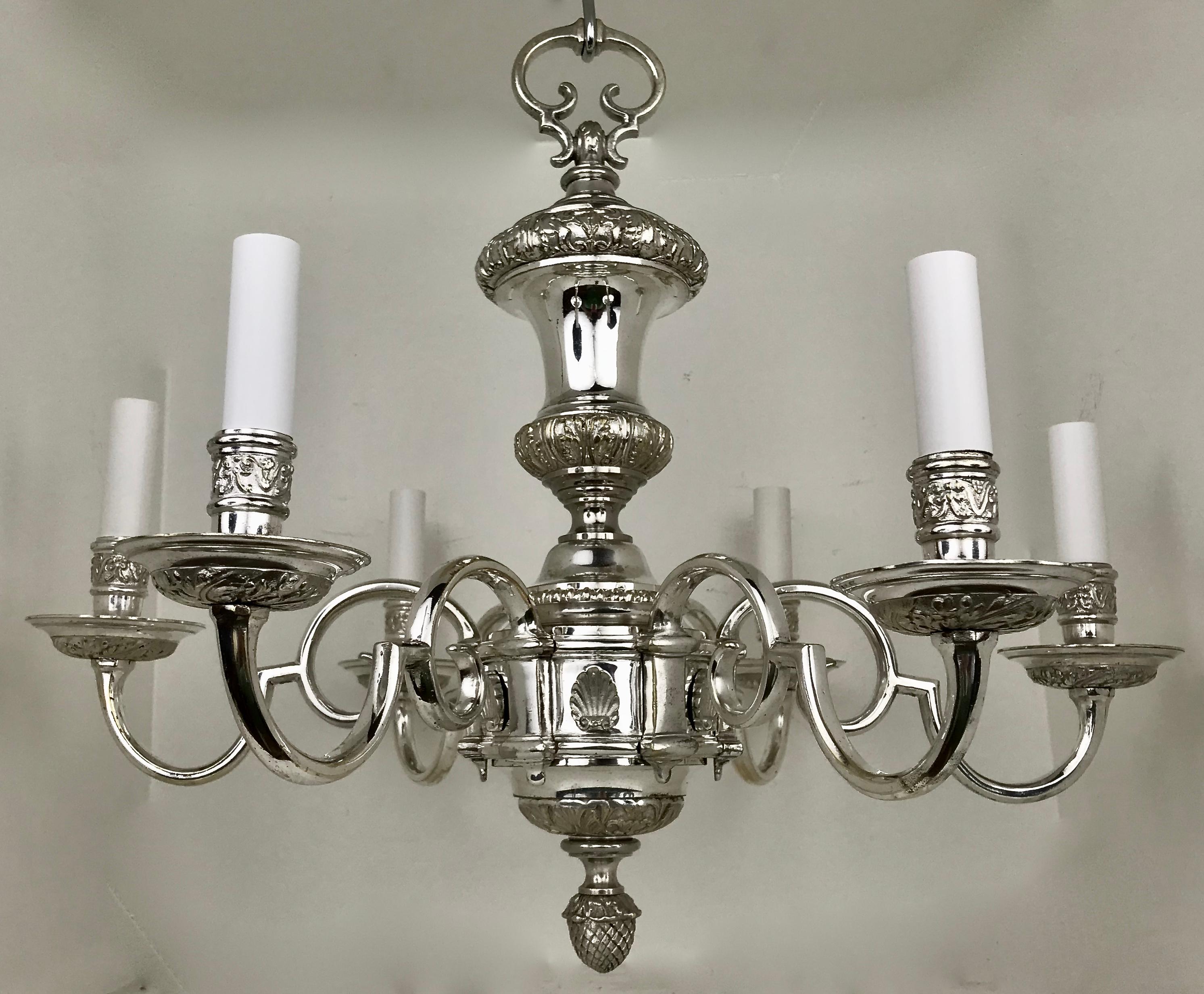 This quality six arm chandelier is beautifully cast, and features a baluster form central shaft. Adorned with scallop shells, it terminates in a pinecone finial.
