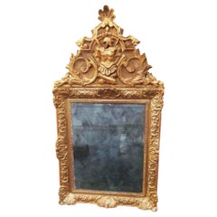 Espejo de madera dorada estilo Regencia a Luis XV con trofeo romano