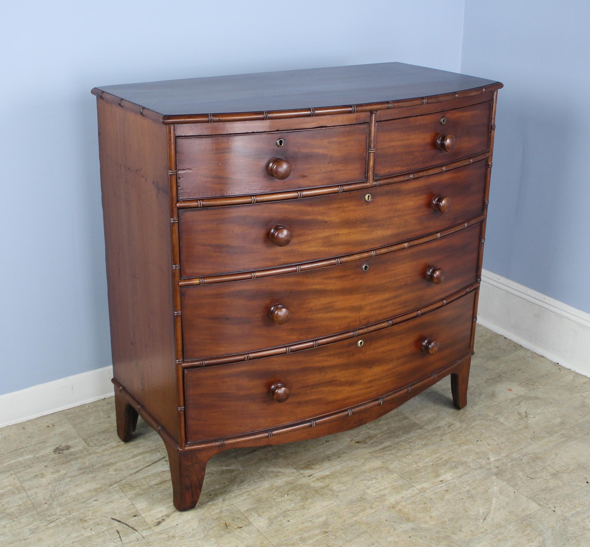 A stunning early English mahogany bowfront chest of drawers in very good condition with very good faux bamboo detail. Original bracket feet and nice grain give this piece eye catching appeal. Drawers open and close snugly and easily.